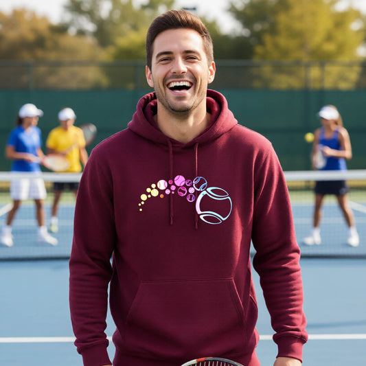A man on a tennis court wearing a maroon hoodie pullover with a graphic of pastel gradient colored tennis balls arcing in flight and gradually getting larger.
