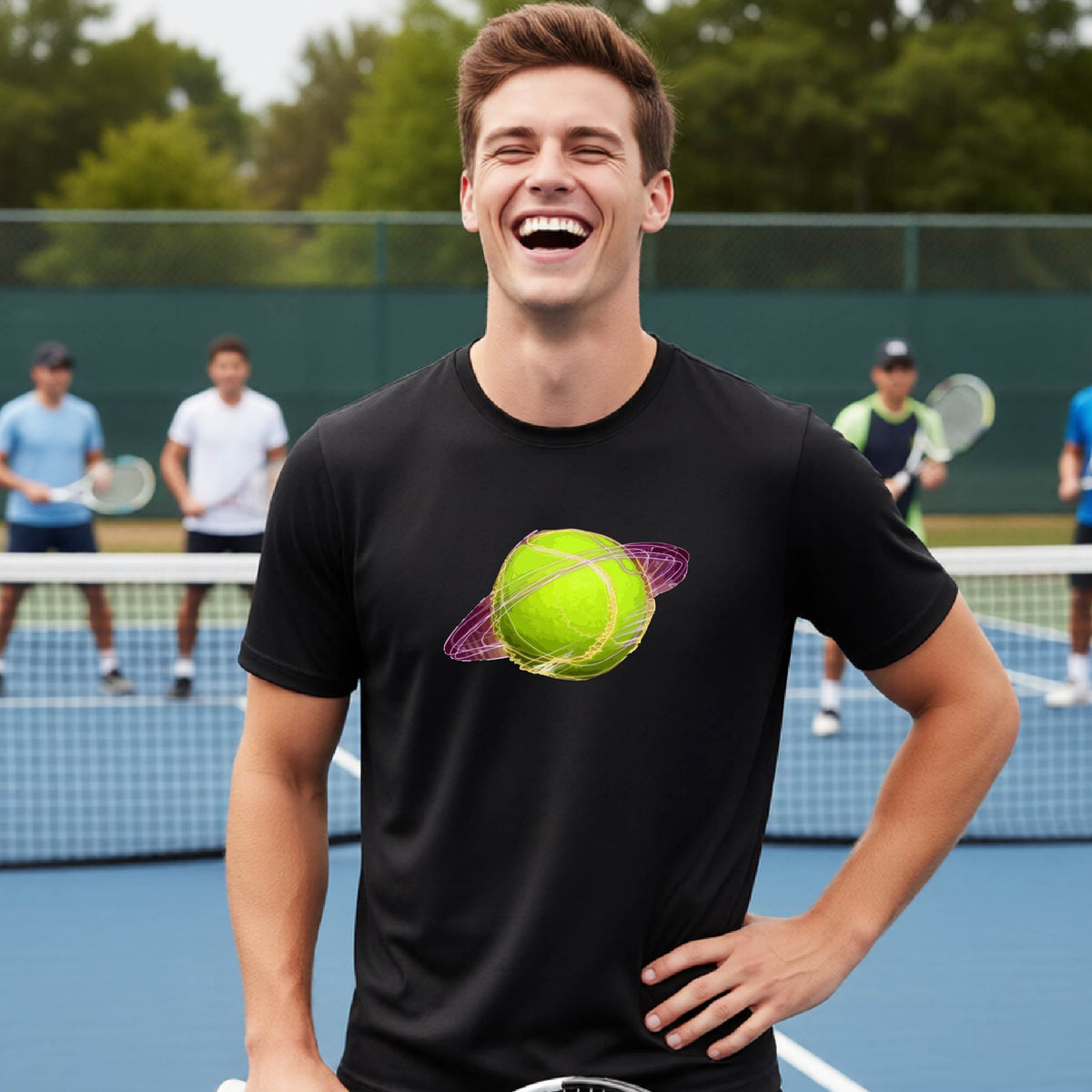A man on a tennis court wearing a black short-sleeve t-shirt with a graphic of a tennis ball in orbit, holding a tennis racket. Other players are visible in the background on the court.
