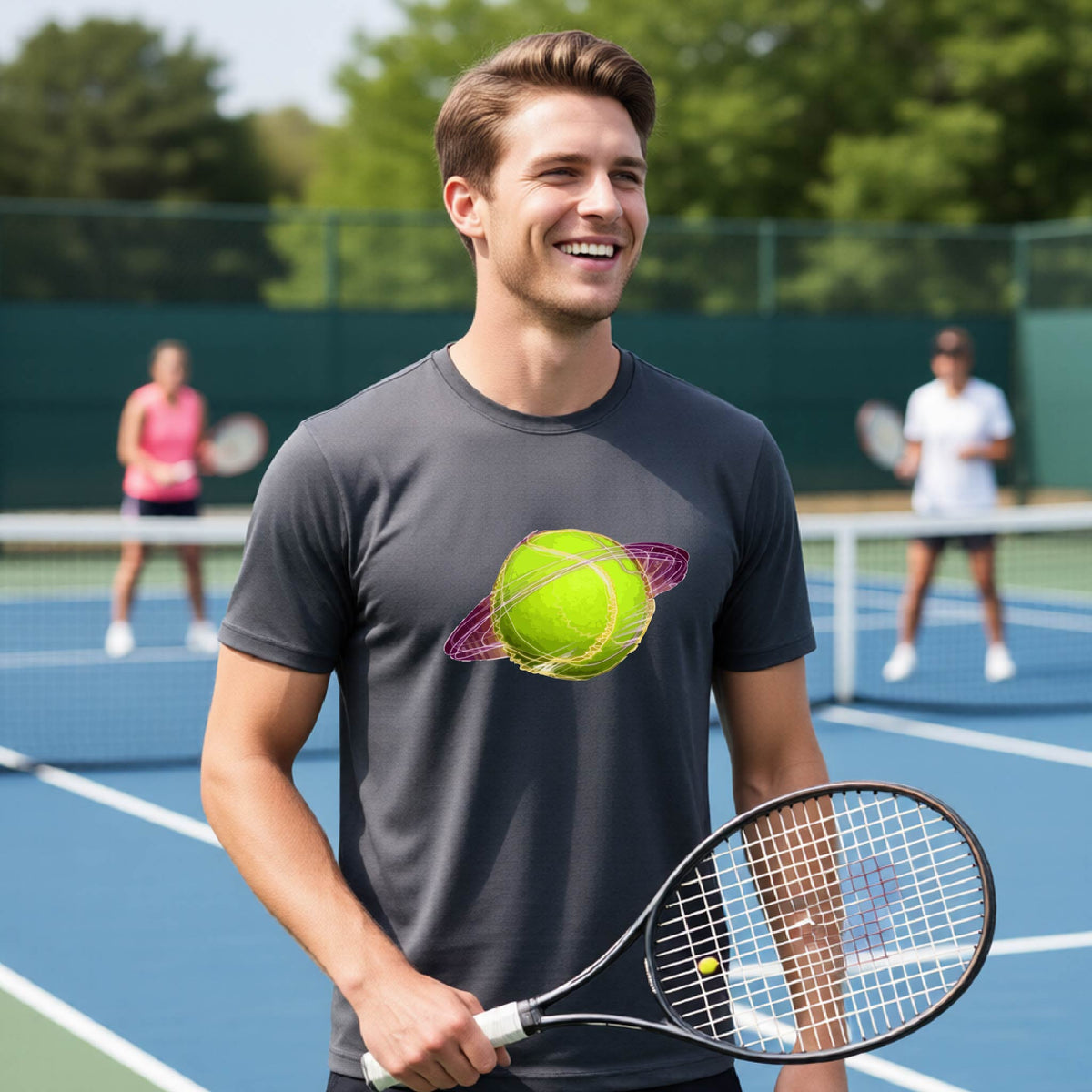 A man on a tennis court wearing a dark gray short-sleeve t-shirt with a graphic of a tennis ball in orbit, holding a tennis racket. Other players are visible in the background on the court.