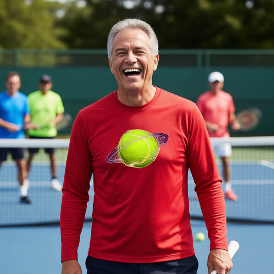 A man on a tennis court wearing a red long-sleeve t-shirt with a graphic of a tennis ball in orbit, holding a tennis racket. Other players are visible in the background on the court.