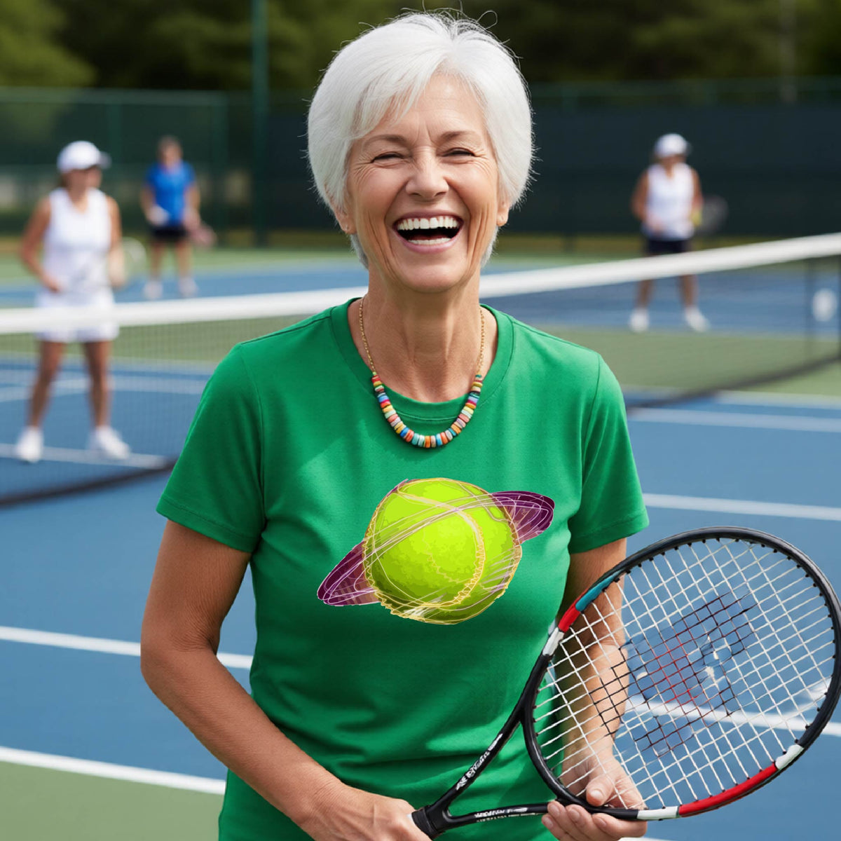 A woman on a tennis court wearing a black short-sleeve t-shirt with a graphic of a tennis ball in orbit, holding a tennis racket. Other players are visible in the background on the court.