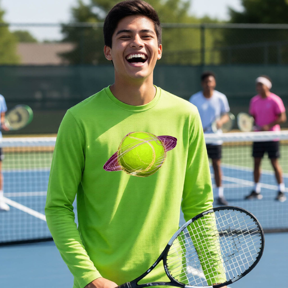 A young person on a tennis court wearing a lime green long-sleeve t-shirt with a graphic of a tennis ball in orbit, holding a tennis racket. Other players are visible in the background on the court.