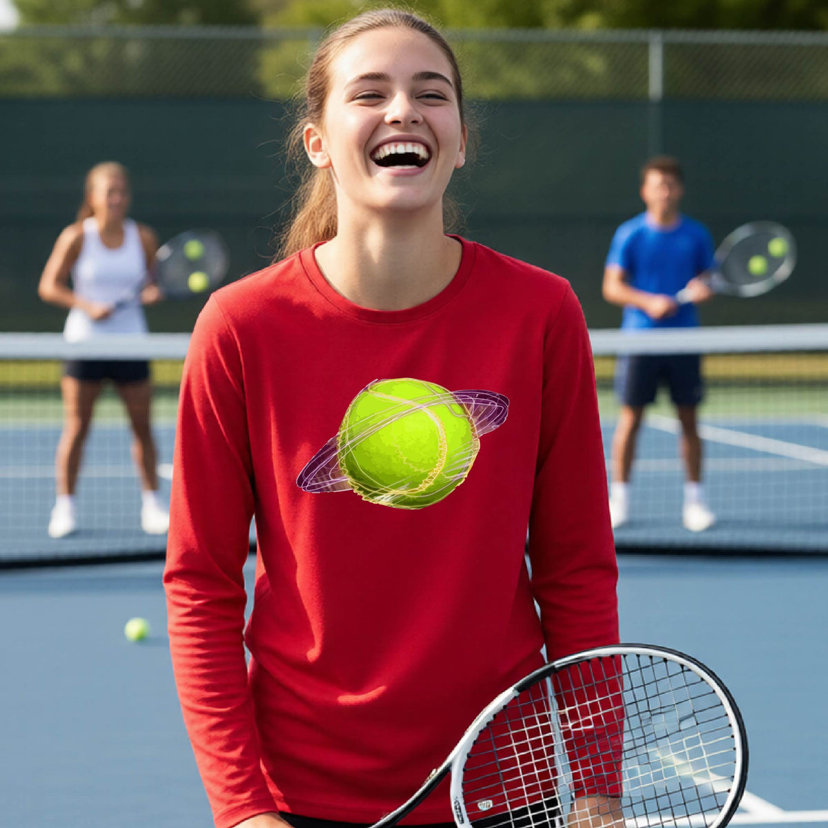 A young person on a tennis court wearing a red long-sleeve t-shirt with a graphic of a tennis ball in orbit, holding a tennis racket. Other players are visible in the background on the court.
