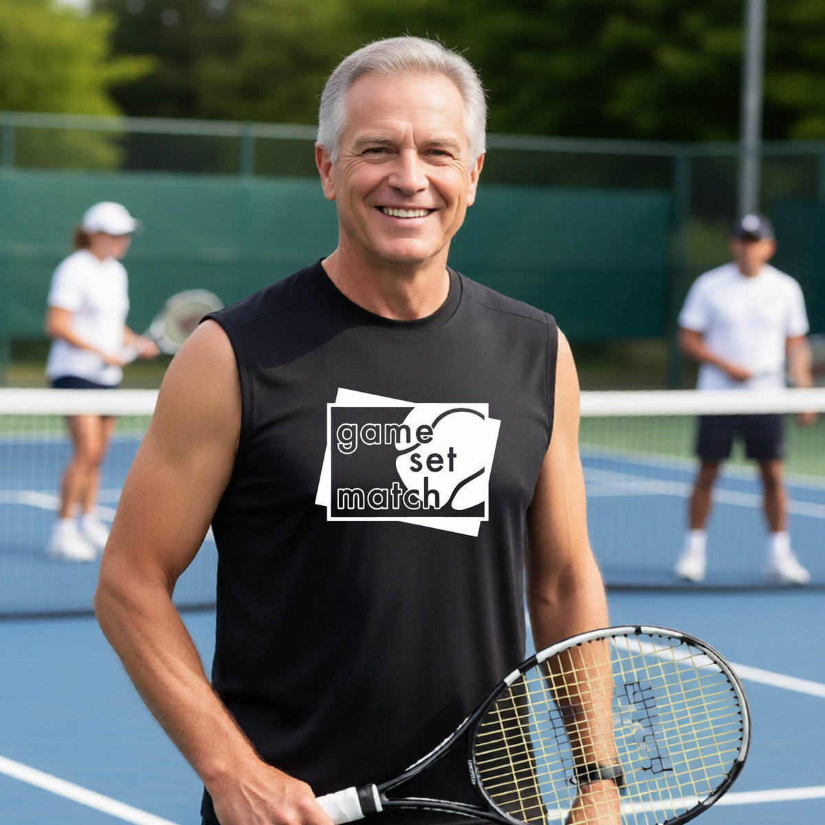 A man on a blue tennis court holds a tennis racket and wears a black long-sleeve T-shirt with a white graphic of two overlapping white and gray squares with the cut out words of ‘GAME SET MATCH” and a tennis ball, printed on the front of the shirt. 