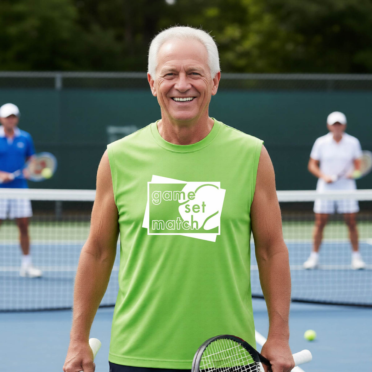 A man on a blue tennis court holds a tennis racket and wears a lime green long-sleeve T-shirt with a white graphic of two overlapping white and gray squares with the cut out words of ‘GAME SET MATCH” and a tennis ball, printed on the front of the shirt. 