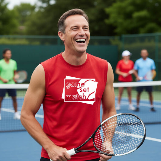 A man on a blue tennis court holds a tennis racket and wears a red long-sleeve T-shirt with a white graphic of two overlapping white and gray squares with the cut out words of ‘GAME SET MATCH” and a tennis ball, printed on the front of the shirt. 