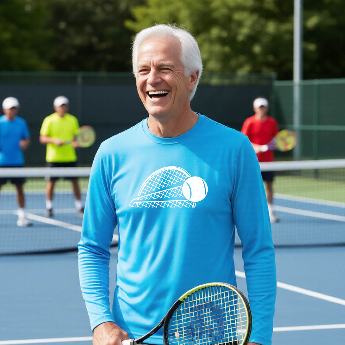 A man on a blue tennis court holds a tennis racket and wears a bright blue long-sleeve T-shirt with a white graphic of a half a tennis racquet with a ball streaking over it. 