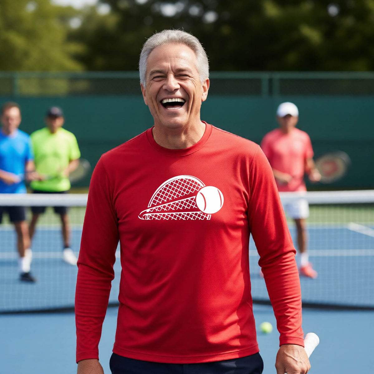 A man on a blue tennis court holds a tennis racket and wears a red long-sleeve T-shirt with a white graphic of a half a tennis racquet with a ball streaking over it. 