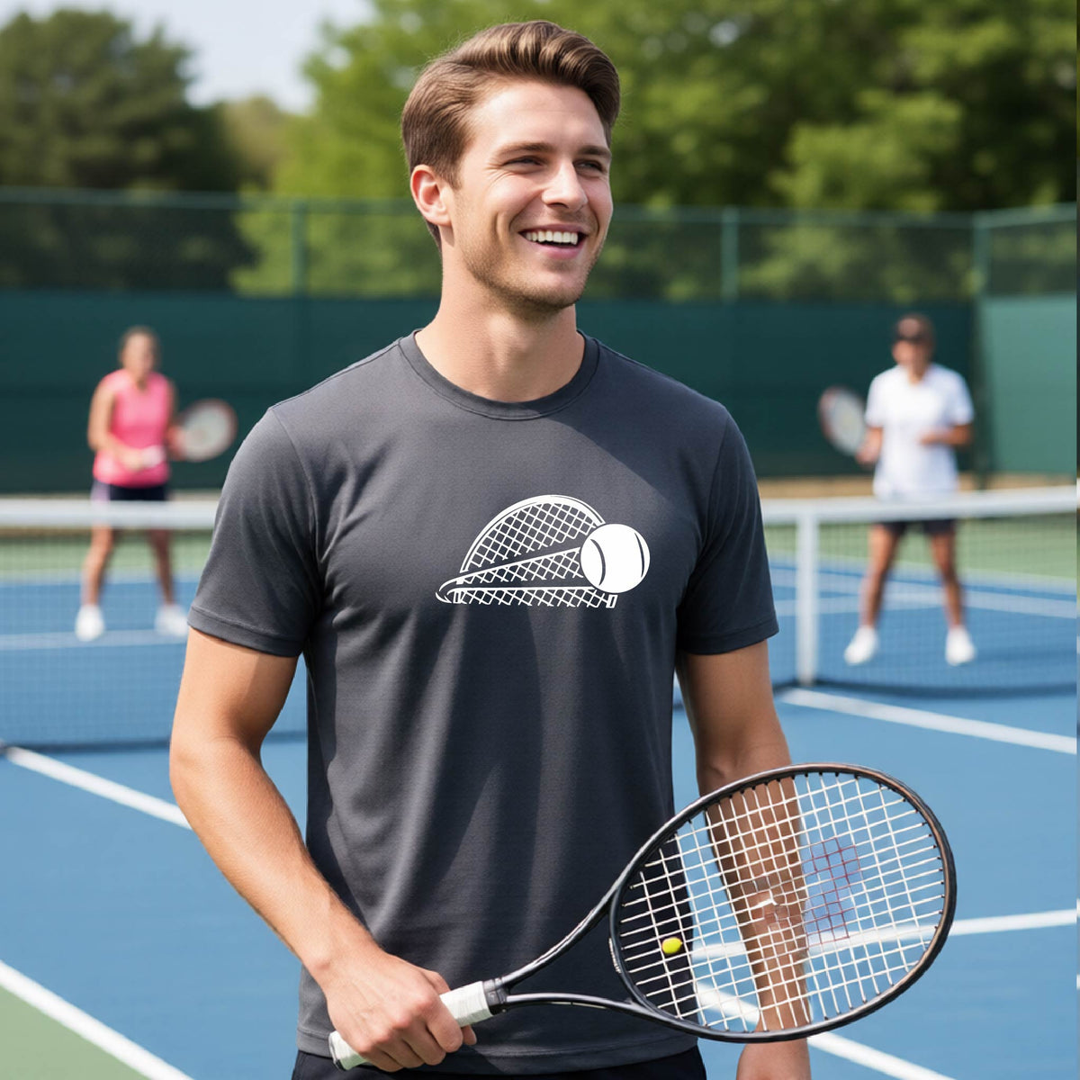 A man on a blue tennis court holds a tennis racket and wears a dark gray short-sleeve T-shirt with a white graphic of a half a tennis racquet with a ball streaking over it. 