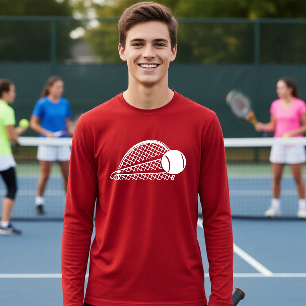A young person on a blue tennis court holds a tennis racket and wears a red long-sleeve T-shirt with a white graphic of a half a tennis racquet with a ball streaking over it. 