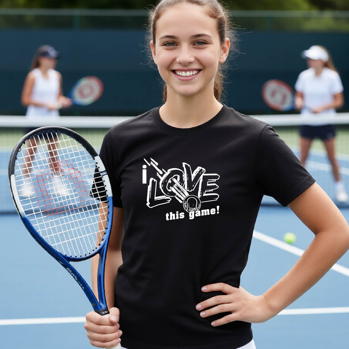 A smiling young woman on a tennis court holds a tennis racket and wears a black graphic T-shirt that reads 'i LOVE this game!' in white lettering.