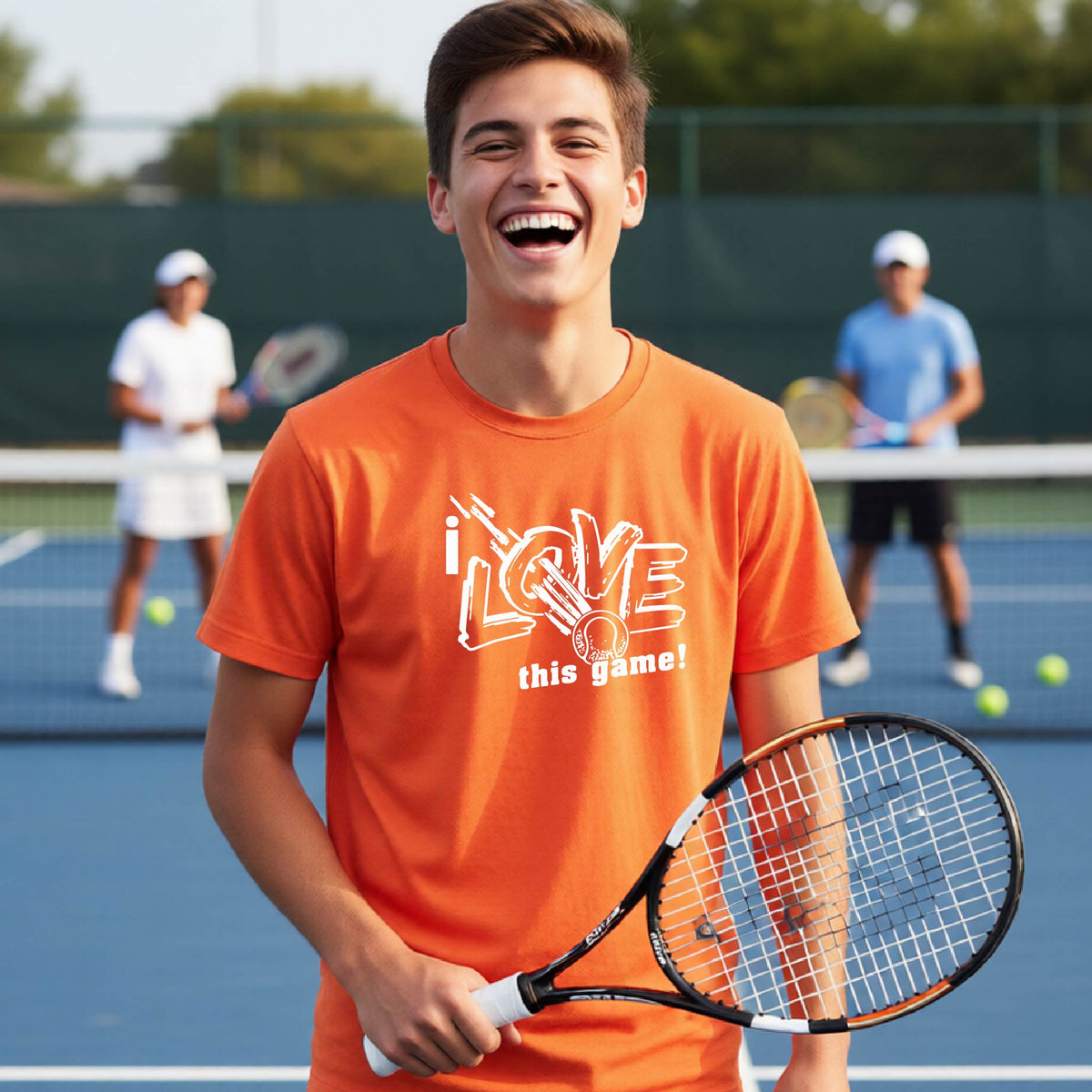 A young man smiling and laughing on a tennis court, wearing an orange t-shirt with the graphic text 'i LOVE this game!' and holding a tennis racket.