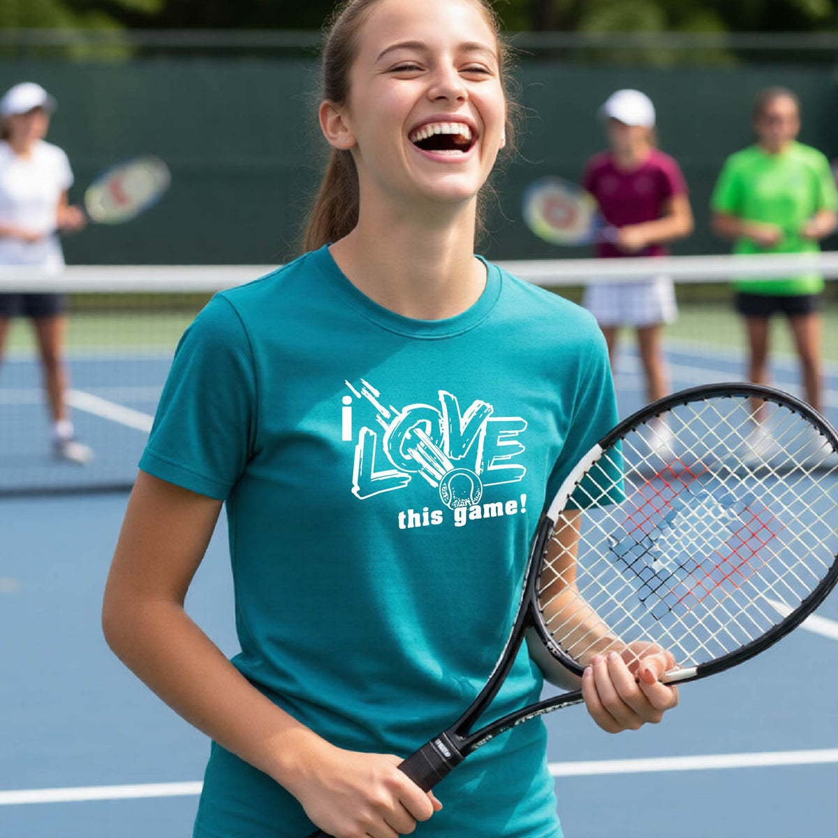 A young woman laughing on a tennis court wearing a teal t-shirt with a white graphic that reads 'i LOVE this game!'. She is holding a tennis racket, with other players blurred in the background.