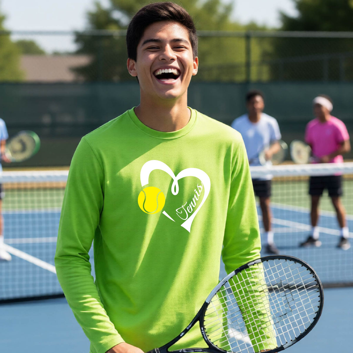 A man laughing on a tennis court wearing a bright lime green long-sleeve shirt with a white heart, tennis ball, and 'Tennis' graphic, holding a tennis racket.