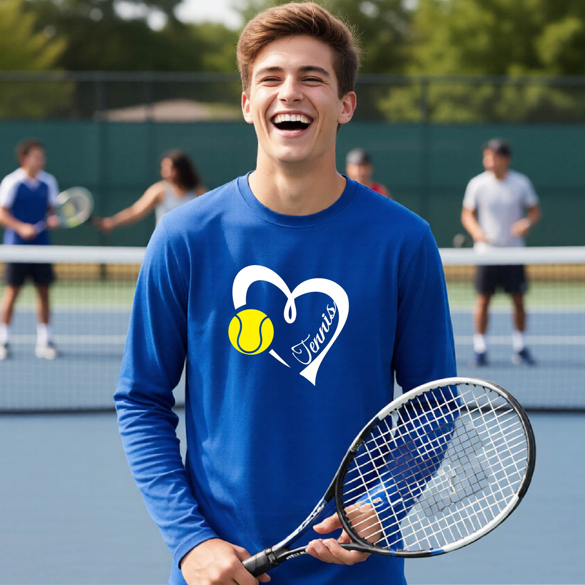 A man laughing on a tennis court wearing a royal blue long-sleeve shirt with a white heart outline, a yellow tennis ball graphic, and the word 'Tennis' in script. He is holding a tennis racket, with other players and a green fence blurred in the background.