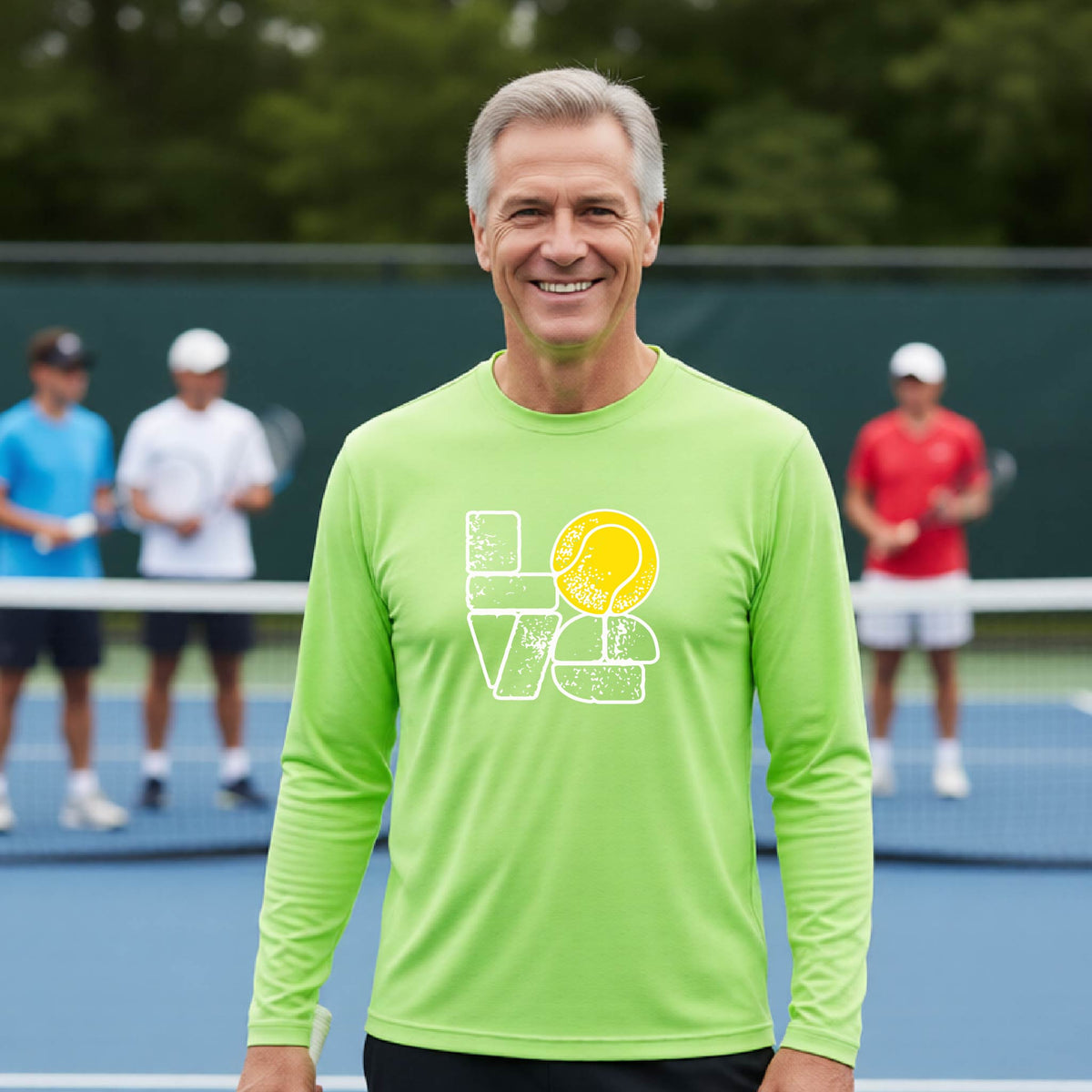 A man wearing a lime green long-sleeve t-shirt with a white and yellow tennis-themed graphic "LOVE" with a tennis ball replacing the O, with a tennis  court and players in the background.