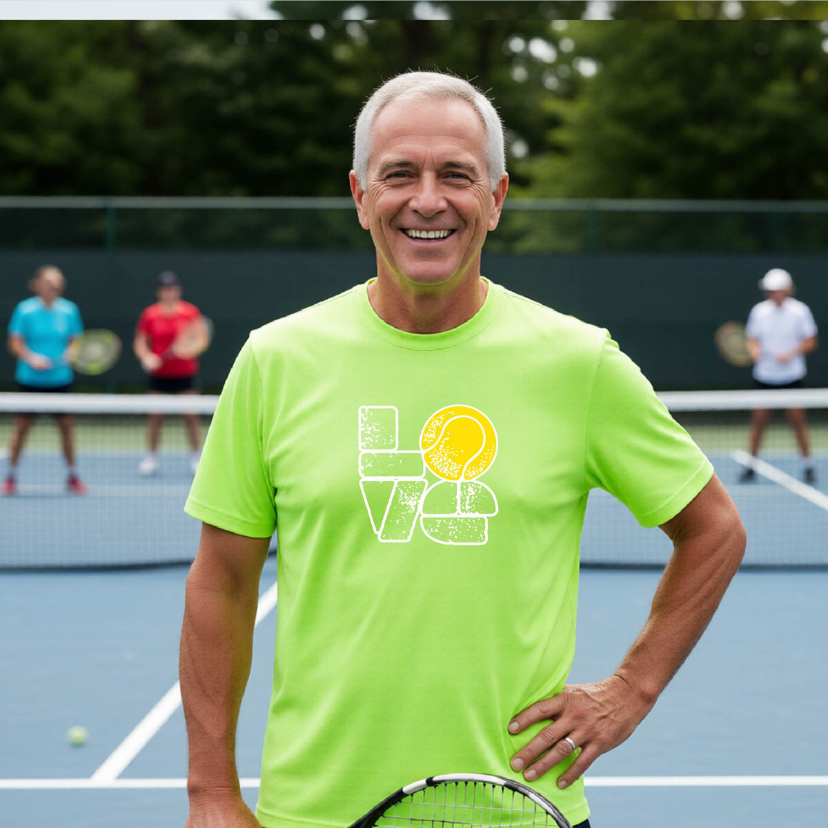 A man wearing a lime green short-sleeve t-shirt with a white and yellow tennis-themed graphic "LOVE" with a tennis ball replacing the O, with a tennis  court and players in the background.