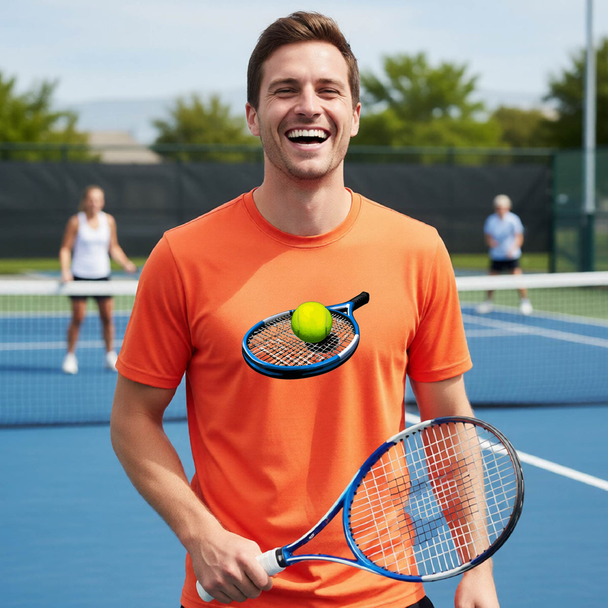 A man on a blue tennis court wearing an orange t-shirt with a graphic of a tennis racket and tennis ball on the chest, holding a tennis racket.