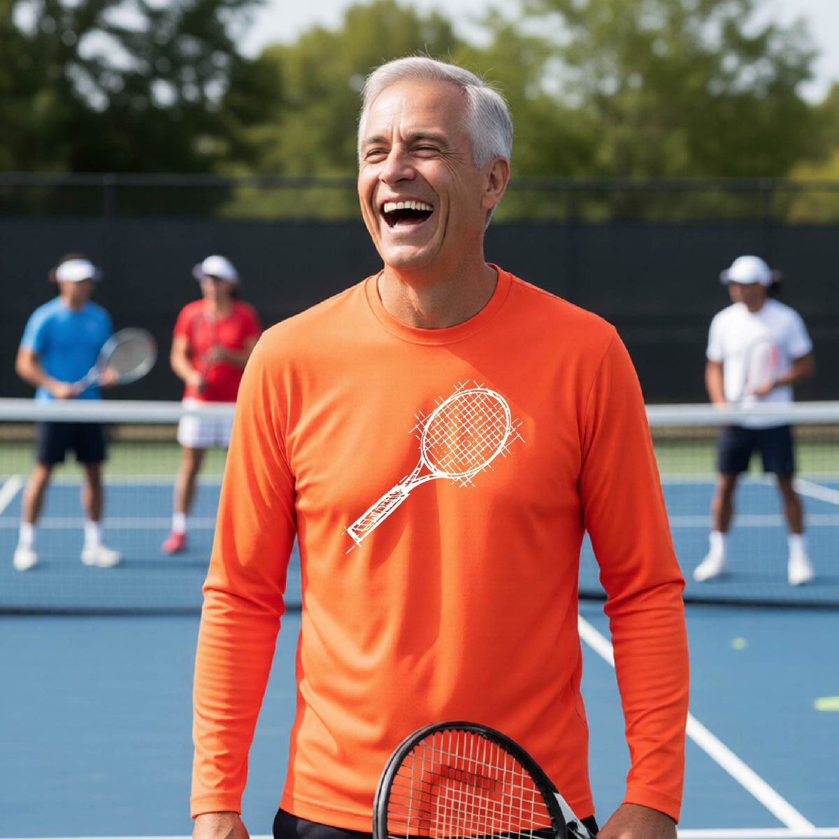 A man on a blue tennis court holds a tennis racket and wears an orange long-sleeve T-shirt with a white retro tennis racquet graphic.  