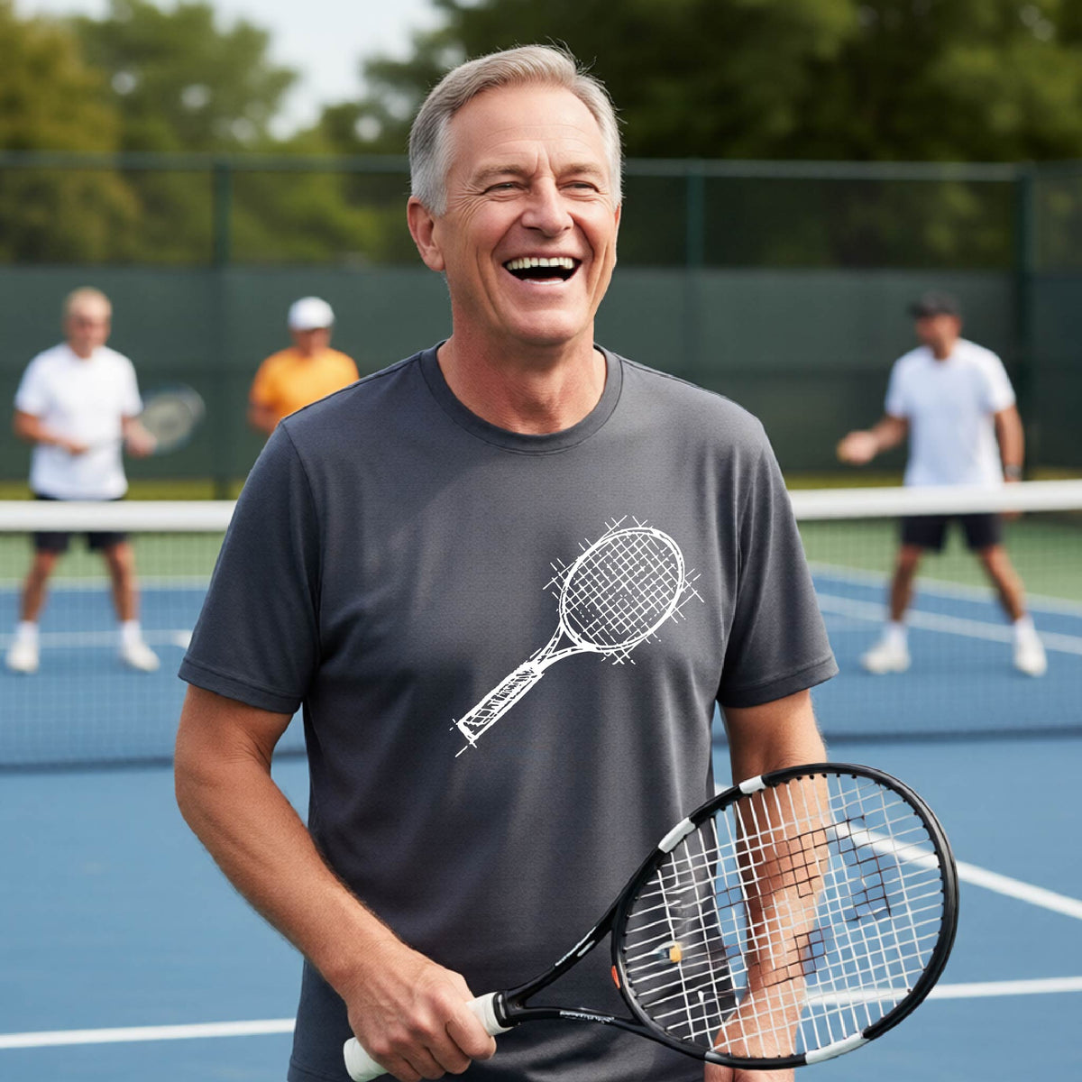 A man on a blue tennis court holds a tennis racket and wears a dark gray short-sleeve T-shirt with a white retro tennis racquet graphic.  