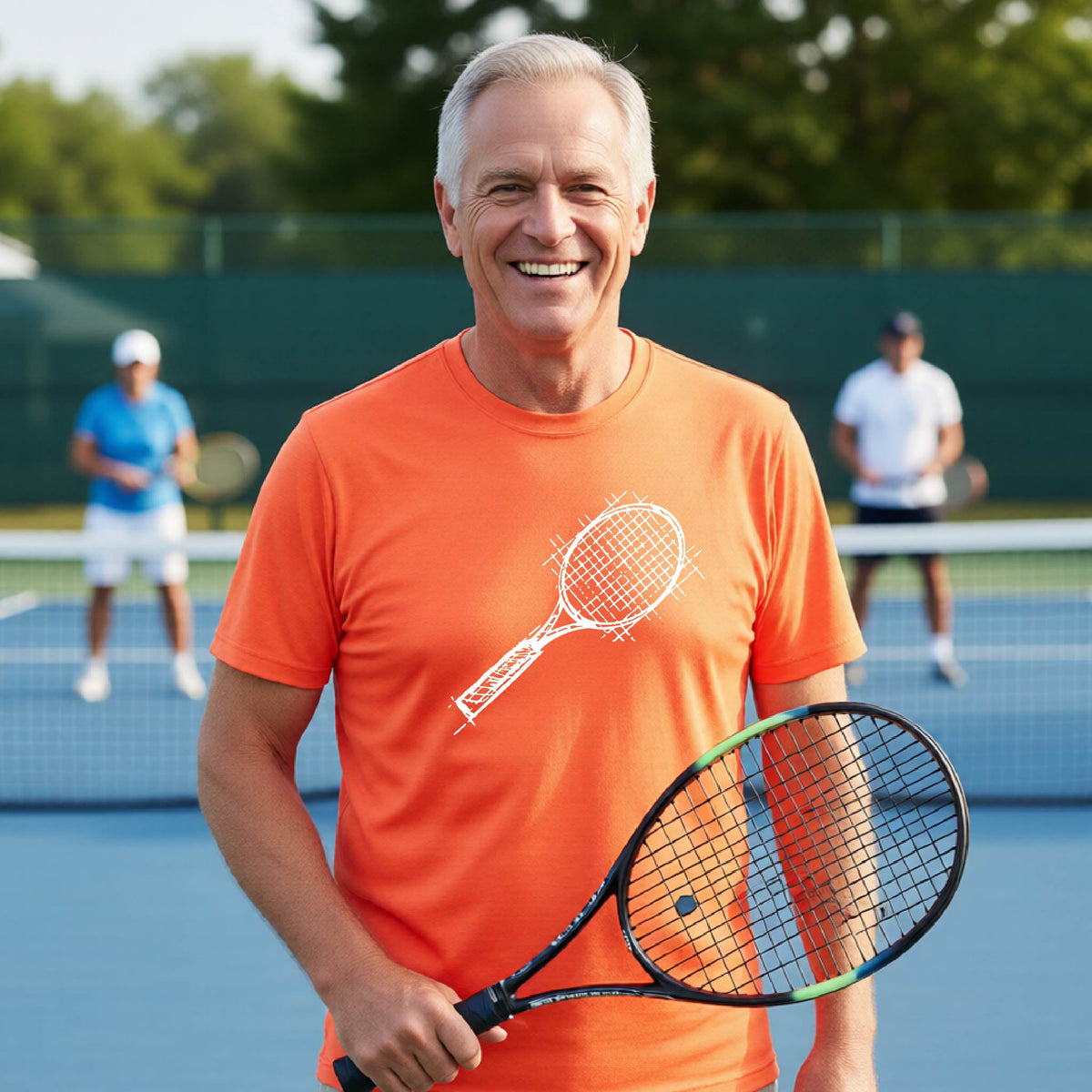 A man on a blue tennis court holds a tennis racket and wears an orange short-sleeve T-shirt with a white retro tennis racquet graphic.  
