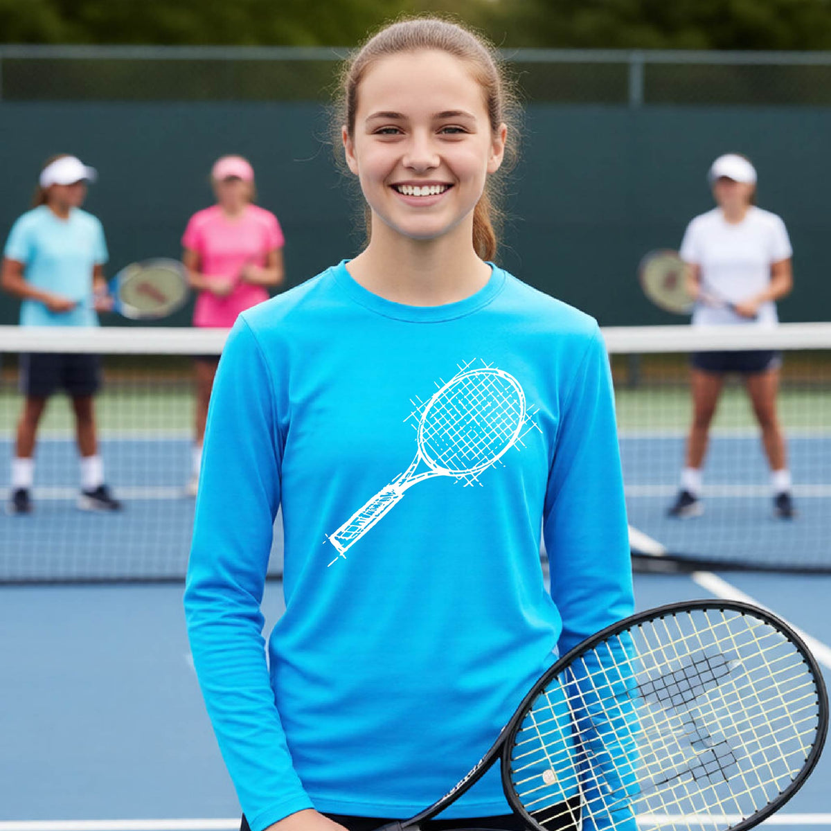 A young person on a blue tennis court holds a tennis racket and wears a bright blue long-sleeve T-shirt with a white retro tennis racquet graphic.  