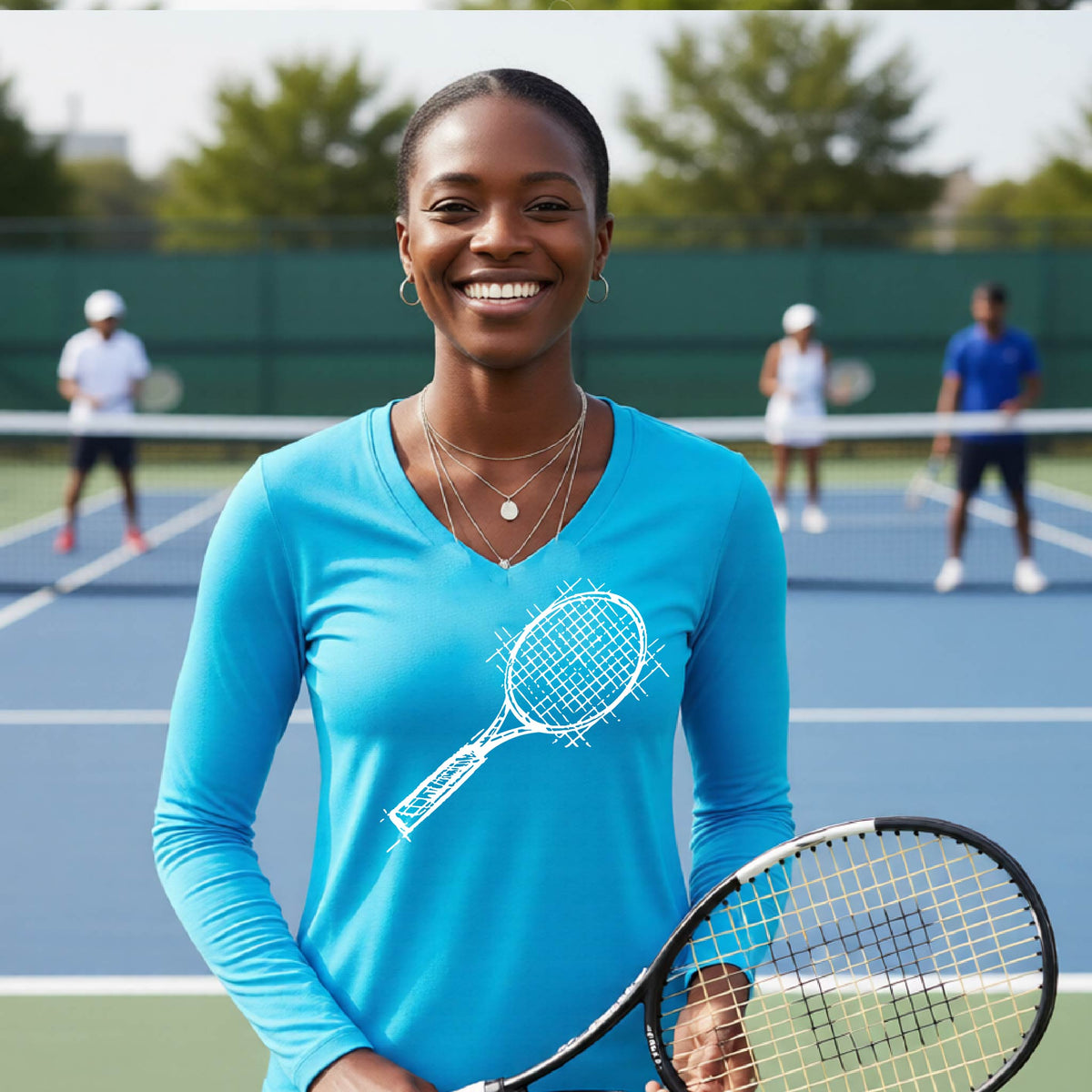 A woman on a blue tennis court holds a tennis racket and wears a bright blue long-sleeve T-shirt with a white retro tennis racquet graphic.  