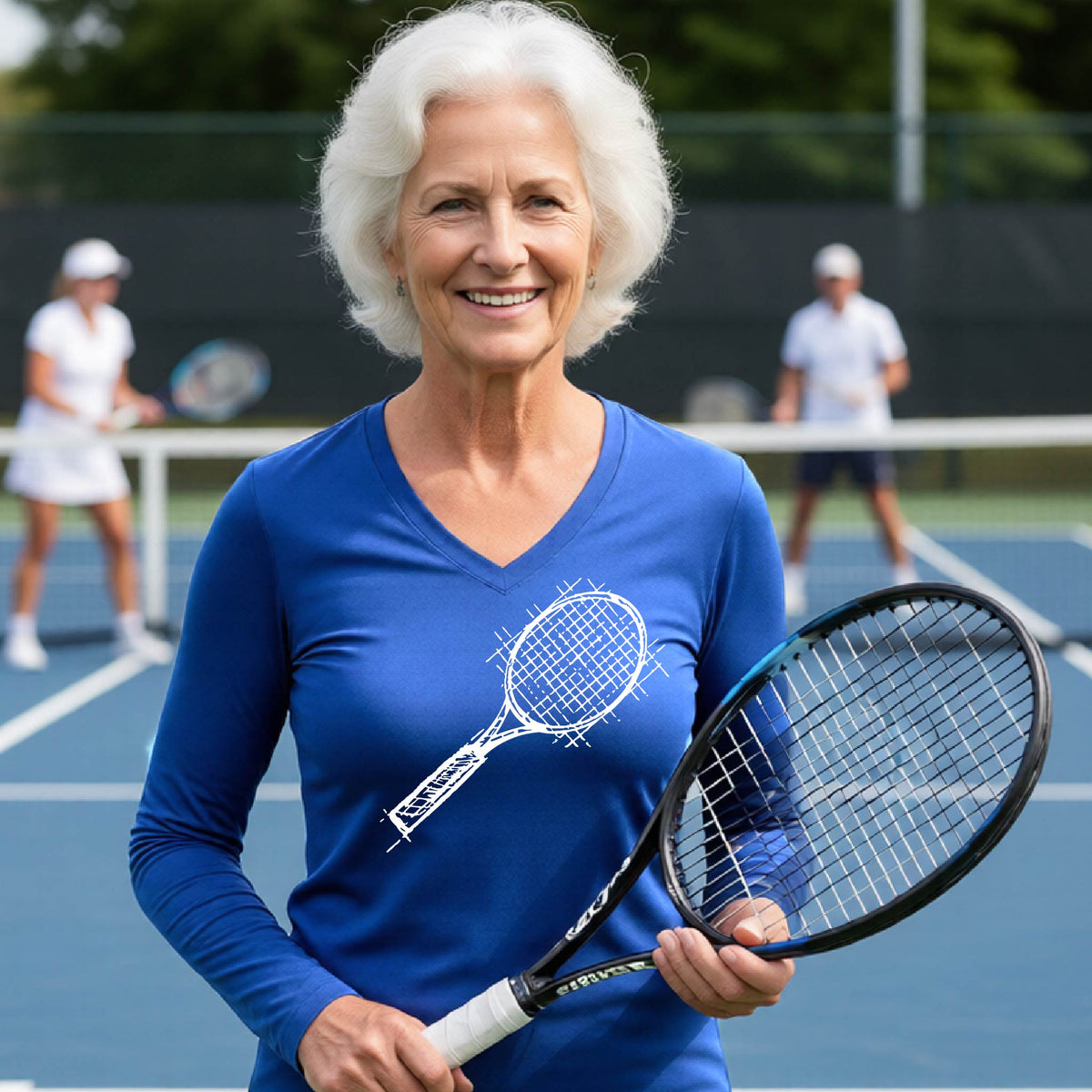 A woman on a blue tennis court holds a tennis racket and wears a royal blue long-sleeve T-shirt with a white retro tennis racquet graphic.  