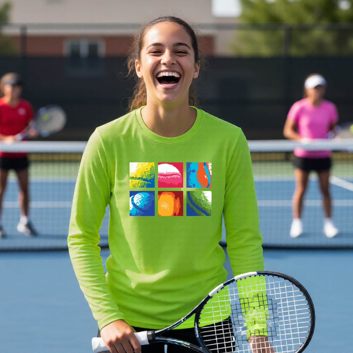 A woman laughing on a tennis court wearing a bright lime green long-sleeve shirt with a colorful graphic print on the chest, holding a tennis racket.