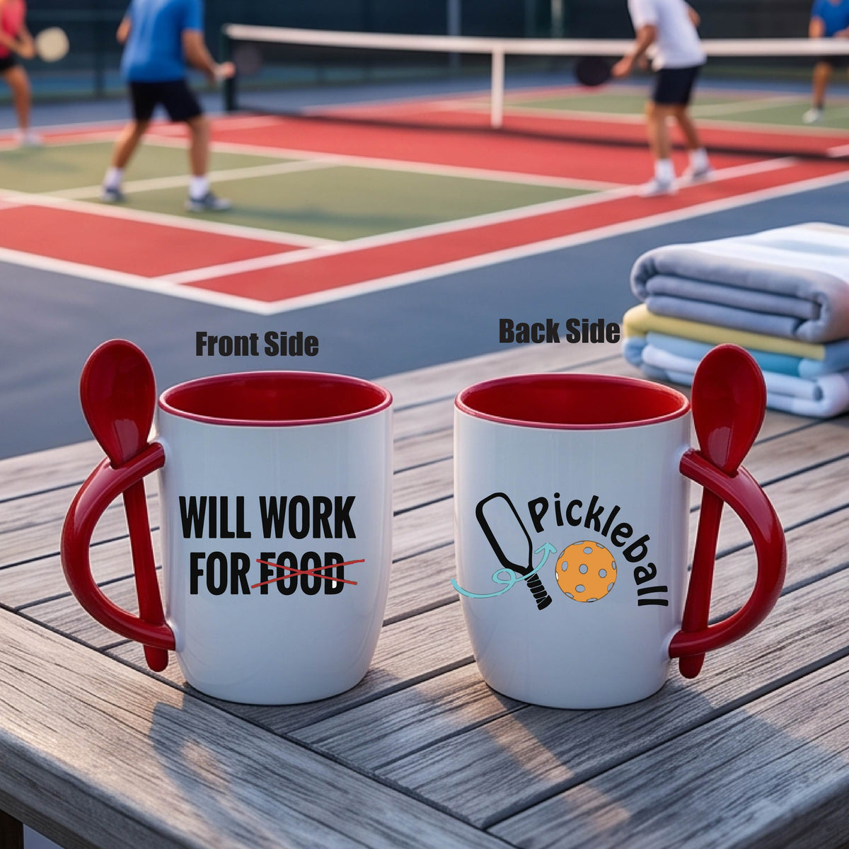 a white and red 12 ounce coffee mug with a built in spoon in the handle with the wraparound text 'WILL WORK FOR FOOD" and a pickleball paddle and ball graphic.