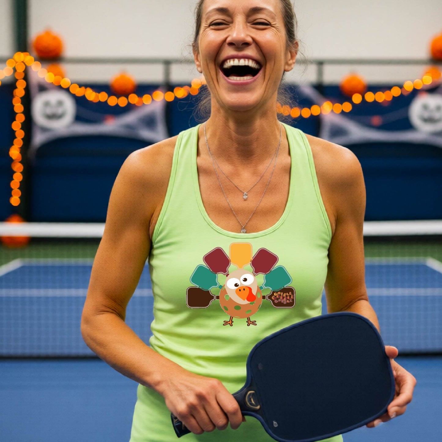 A lime green racerback tank top featuring a graphic of a cartoon turkey. The turkey's tail feathers are depicted as colorful pickleball paddles in shades of yellow, maroon, teal, and brown,.