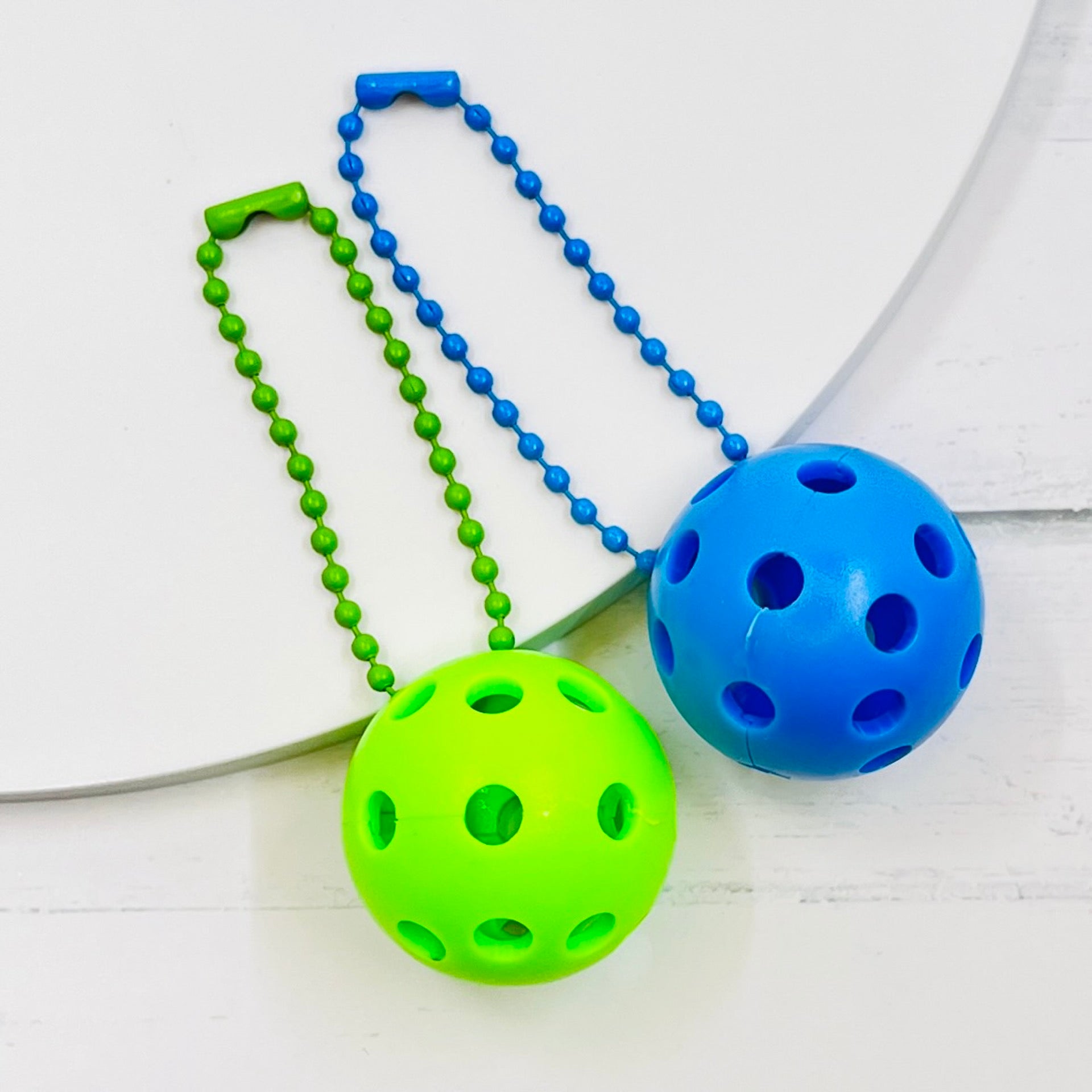 Micro Pickleball Bag Tags/Pulls (Set of 2)  Each order gets you 2 of the cutest little pickleball and chain! They measure about 1 inch and are used as bag tag markers. Fun for any bag, especially your pickleball bag!! The balls come in 4 colors: Red, Green, Blue, and Yellow. They now also come with matching chain colors!! Choose from 4 fun colors.