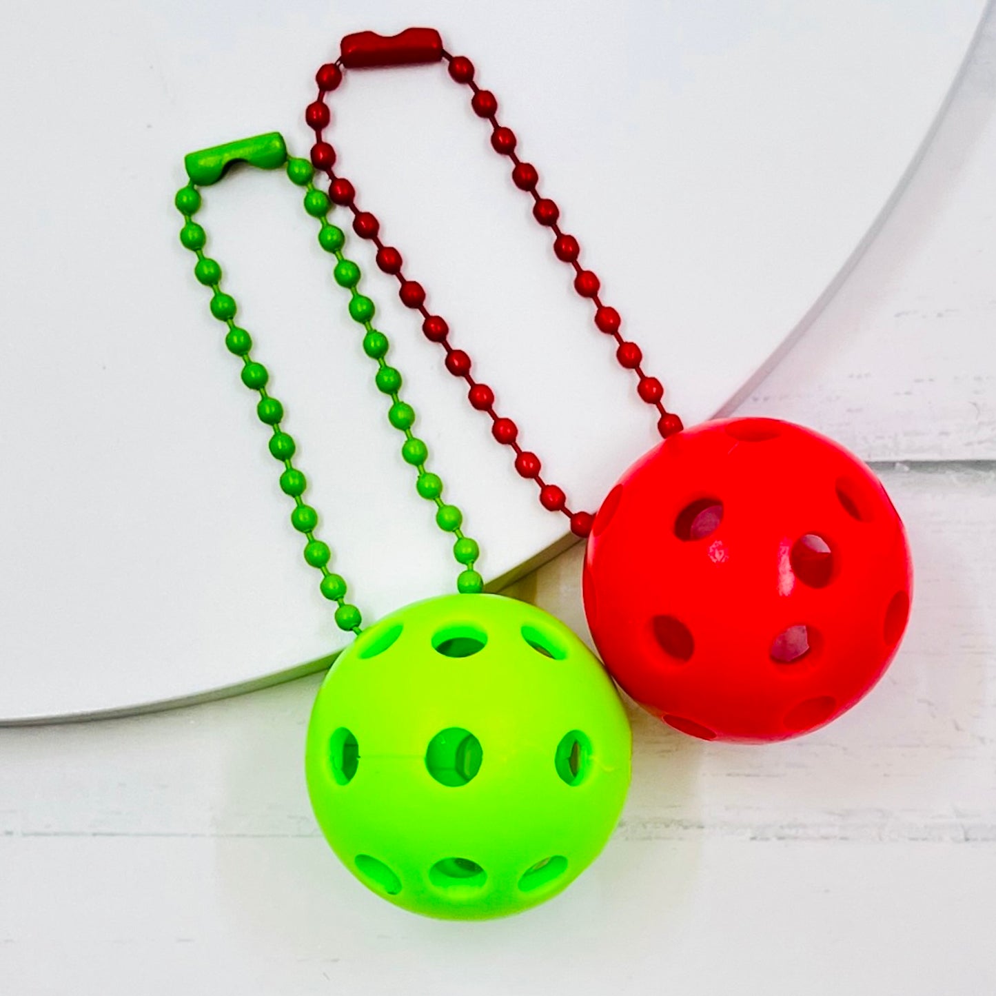 Micro Pickleball Bag Tags/Pulls (Set of 2)  Each order gets you 2 of the cutest little pickleball and chain! They measure about 1 inch and are used as bag tag markers. Fun for any bag, especially your pickleball bag!! The balls come in 4 colors: Red, Green, Blue, and Yellow. They now also come with matching chain colors!! Choose from 4 fun colors.