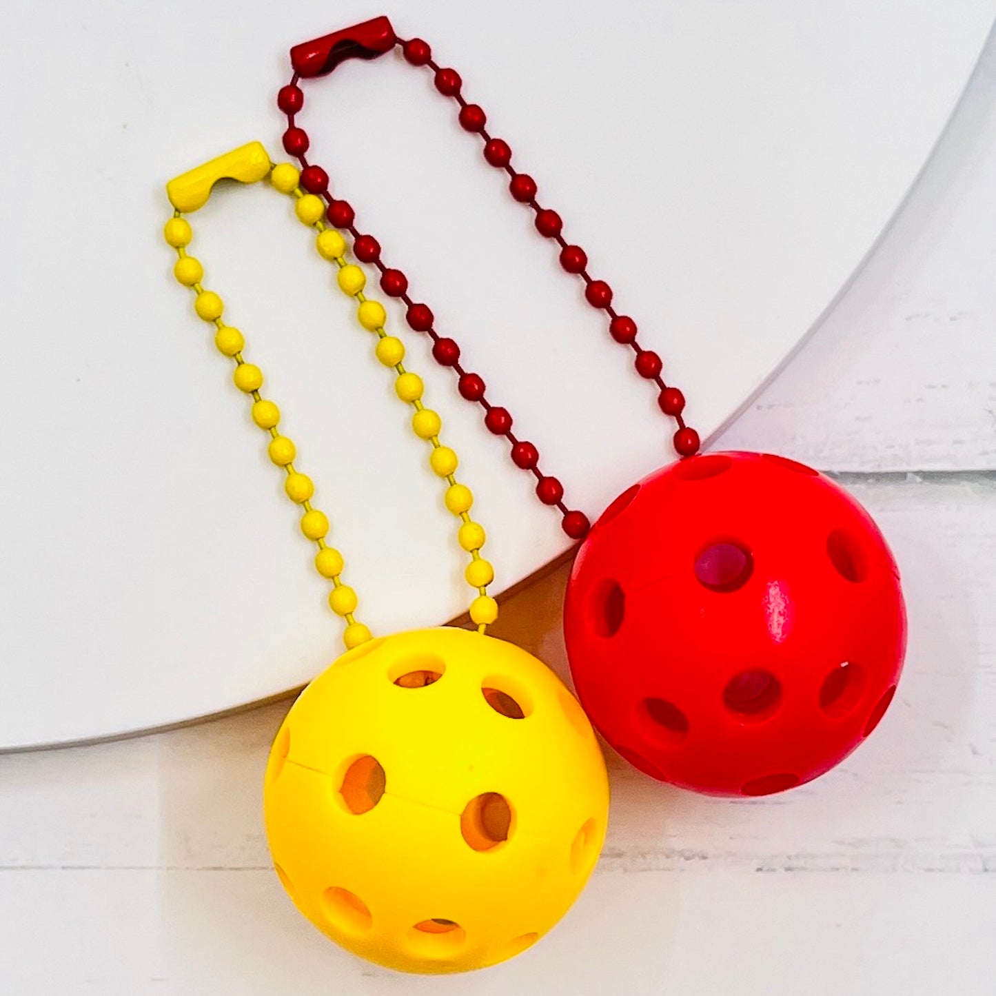 Micro Pickleball Bag Tags/Pulls (Set of 2)  Each order gets you 2 of the cutest little pickleball and chain! They measure about 1 inch and are used as bag tag markers. Fun for any bag, especially your pickleball bag!! The balls come in 4 colors: Red, Green, Blue, and Yellow. They now also come with matching chain colors!! Choose from 4 fun colors.