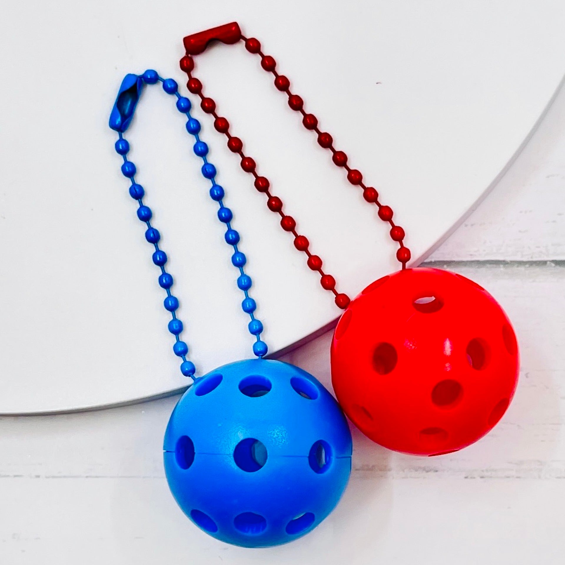 Micro Pickleball Bag Tags/Pulls (Set of 2)  Each order gets you 2 of the cutest little pickleball and chain! They measure about 1 inch and are used as bag tag markers. Fun for any bag, especially your pickleball bag!! The balls come in 4 colors: Red, Green, Blue, and Yellow. They now also come with matching chain colors!! Choose from 4 fun colors.