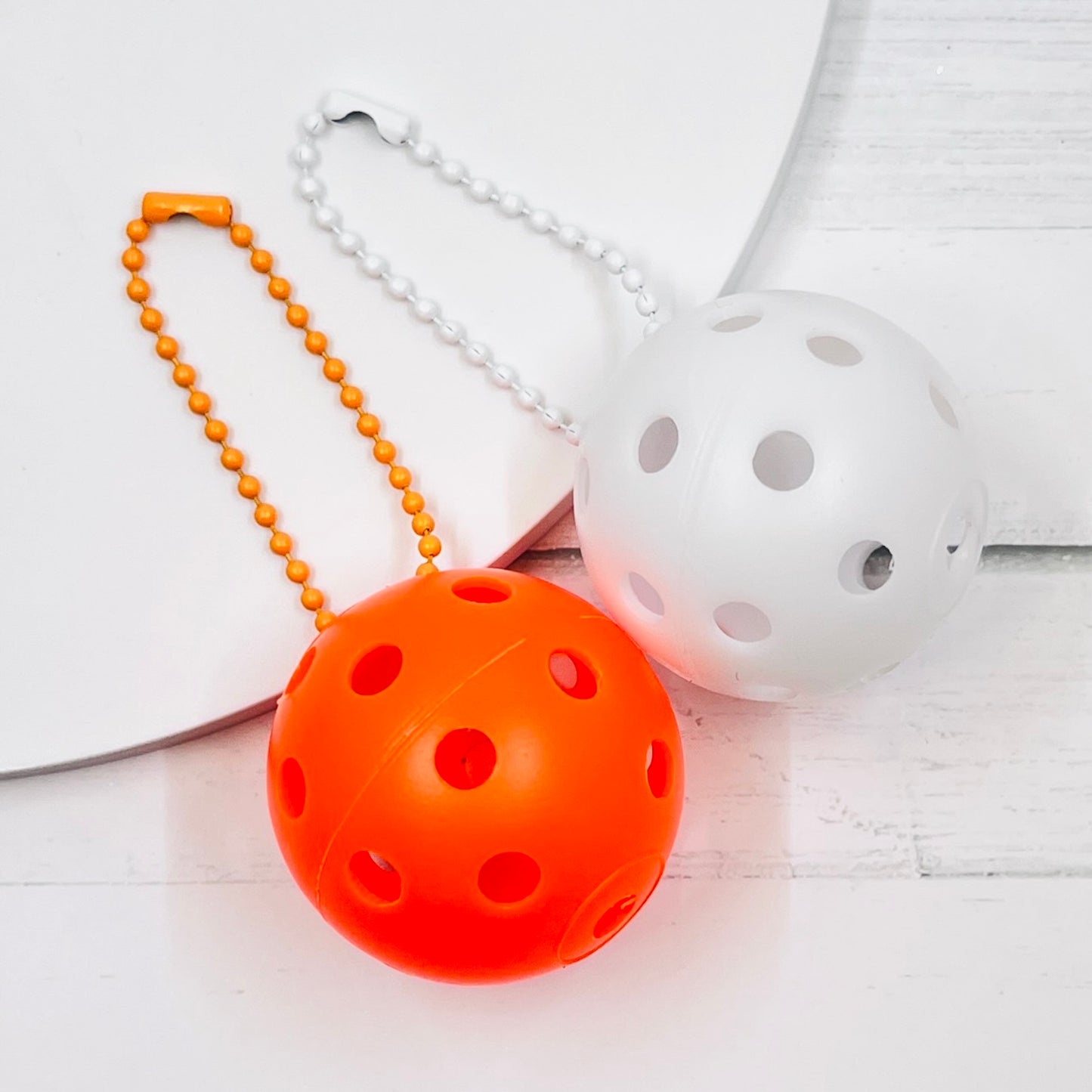 Mini Pickleball Bag Tags/Pulls (Set of 2)  Each order gets you 2 of the little mini pickleballs and chain! They measure about 1 1/2 inches and are used as bag tag markers. Fun for any bag, especially your pickleball bag!! The balls come in 7 colors: Red, Green, Blue, Orange, White, Pink, and Yellow. Choose 2 of the 7 fun colors.