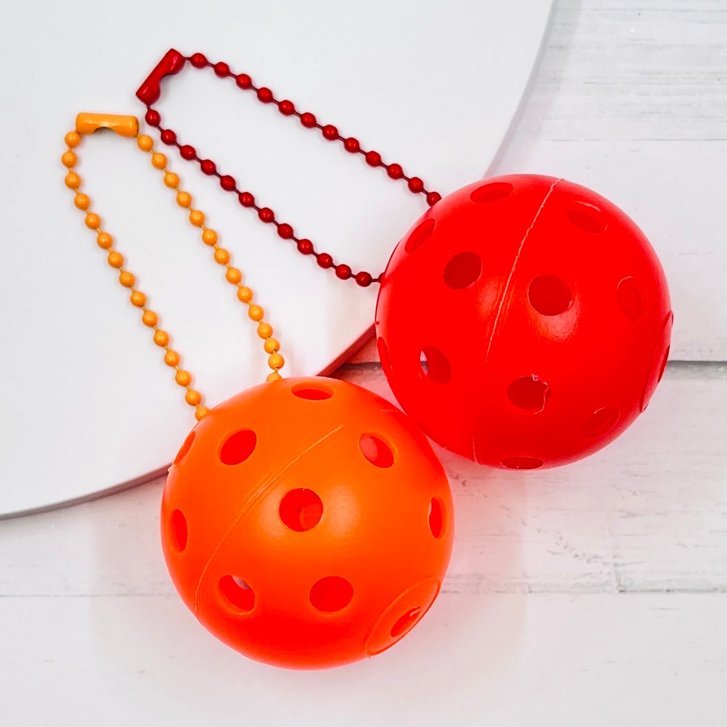 Mini Pickleball Bag Tags/Pulls (Set of 2)  Each order gets you 2 of the little mini pickleballs and chain! They measure about 1 1/2 inches and are used as bag tag markers. Fun for any bag, especially your pickleball bag!! The balls come in 7 colors: Red, Green, Blue, Orange, White, Pink, and Yellow. Choose 2 of the 7 fun colors.