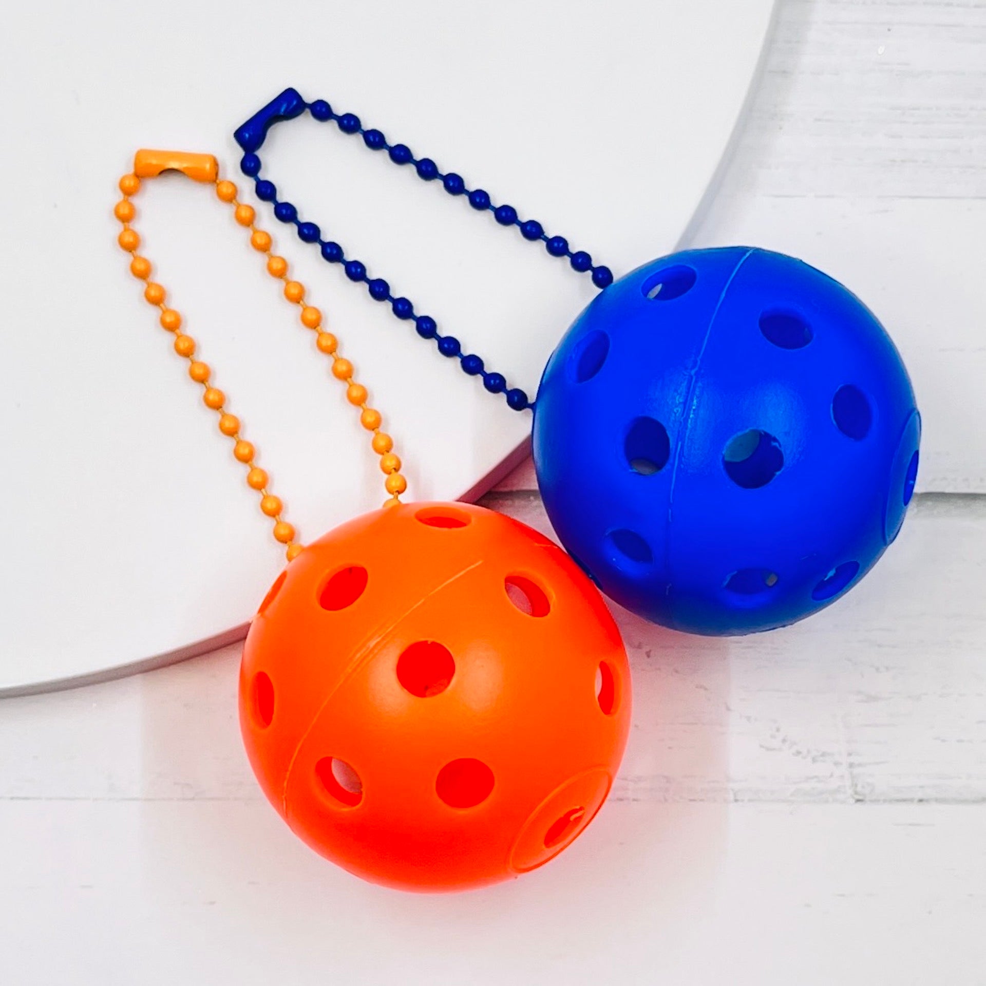 Mini Pickleball Bag Tags/Pulls (Set of 2)  Each order gets you 2 of the little mini pickleballs and chain! They measure about 1 1/2 inches and are used as bag tag markers. Fun for any bag, especially your pickleball bag!! The balls come in 7 colors: Red, Green, Blue, Orange, White, Pink, and Yellow. Choose 2 of the 7 fun colors.