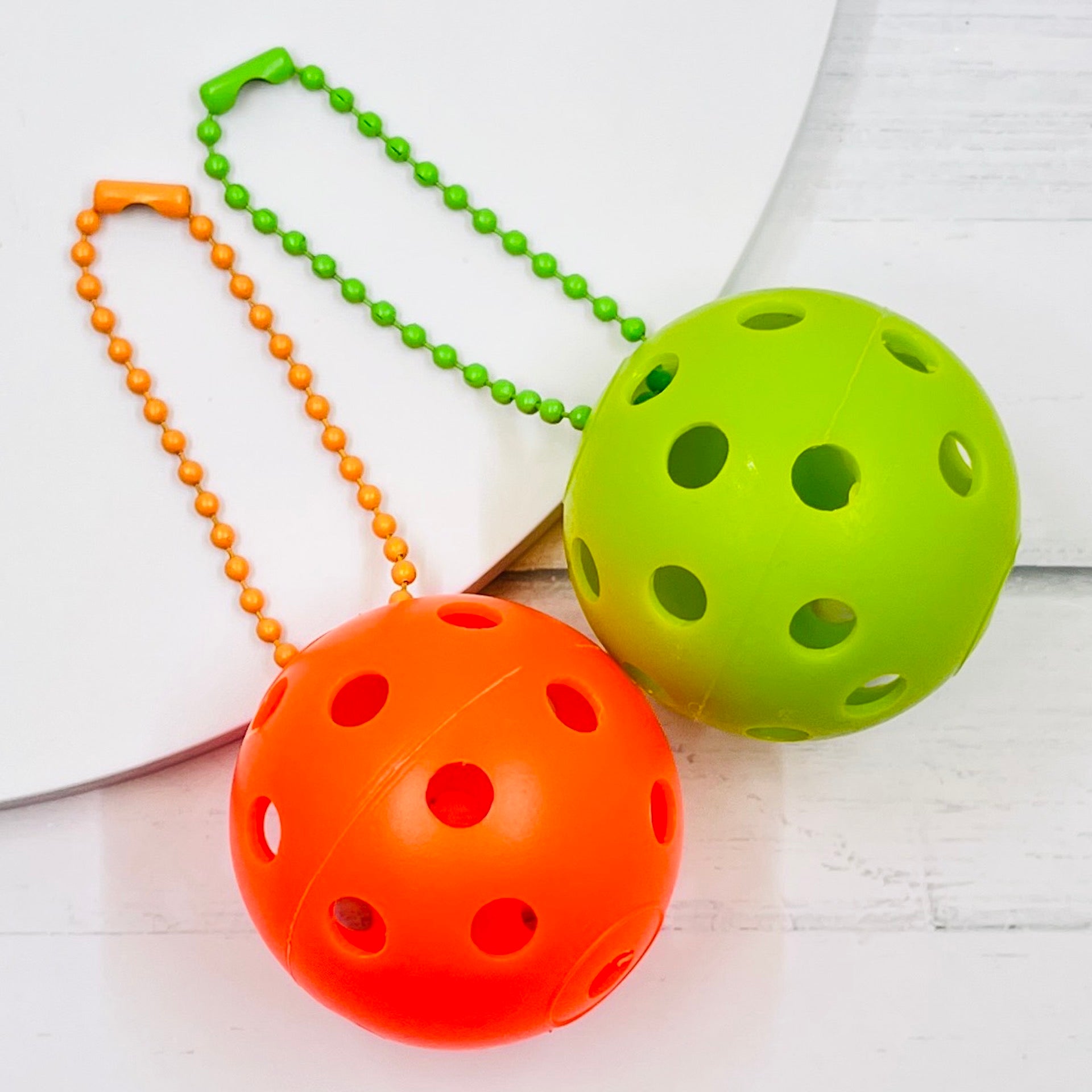 Mini Pickleball Bag Tags/Pulls (Set of 2)  Each order gets you 2 of the little mini pickleballs and chain! They measure about 1 1/2 inches and are used as bag tag markers. Fun for any bag, especially your pickleball bag!! The balls come in 7 colors: Red, Green, Blue, Orange, White, Pink, and Yellow. Choose 2 of the 7 fun colors.
