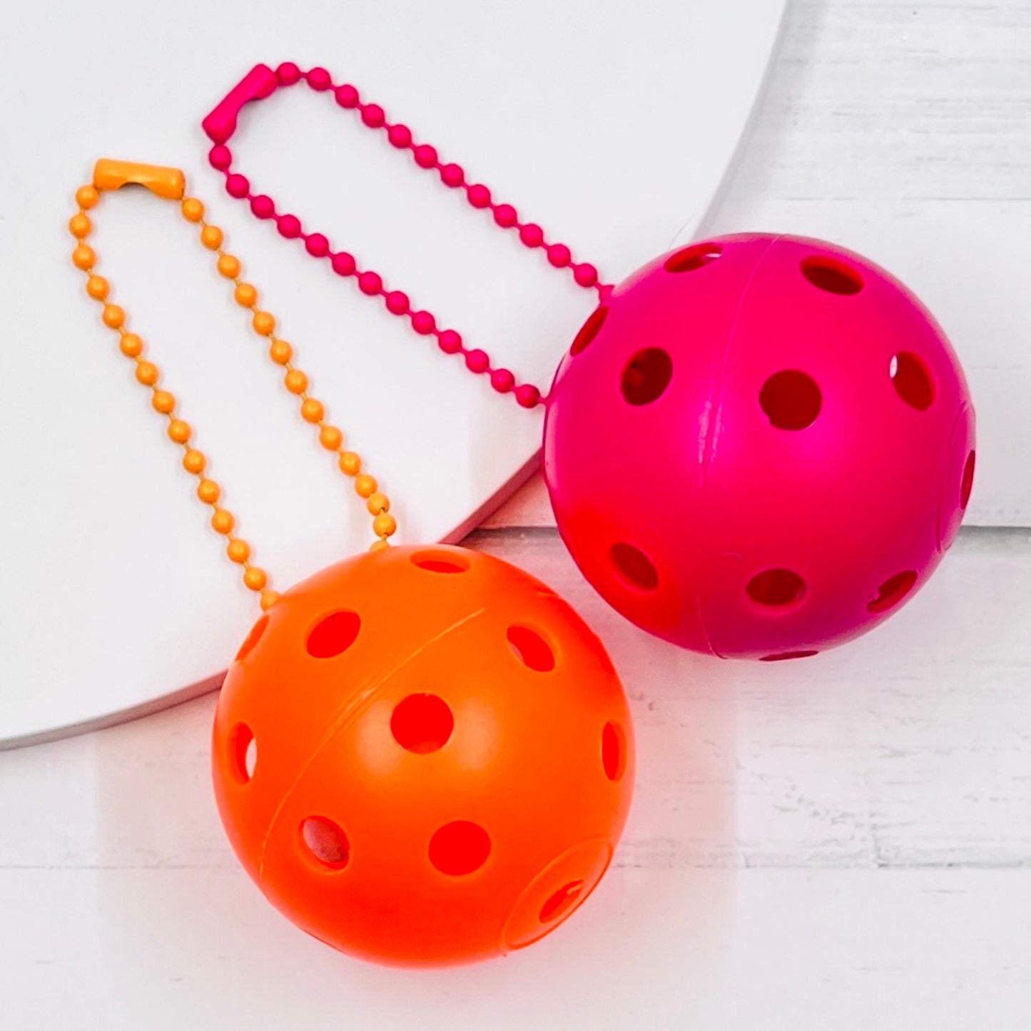 Mini Pickleball Bag Tags/Pulls (Set of 2)  Each order gets you 2 of the little mini pickleballs and chain! They measure about 1 1/2 inches and are used as bag tag markers. Fun for any bag, especially your pickleball bag!! The balls come in 7 colors: Red, Green, Blue, Orange, White, Pink, and Yellow. Choose 2 of the 7 fun colors.