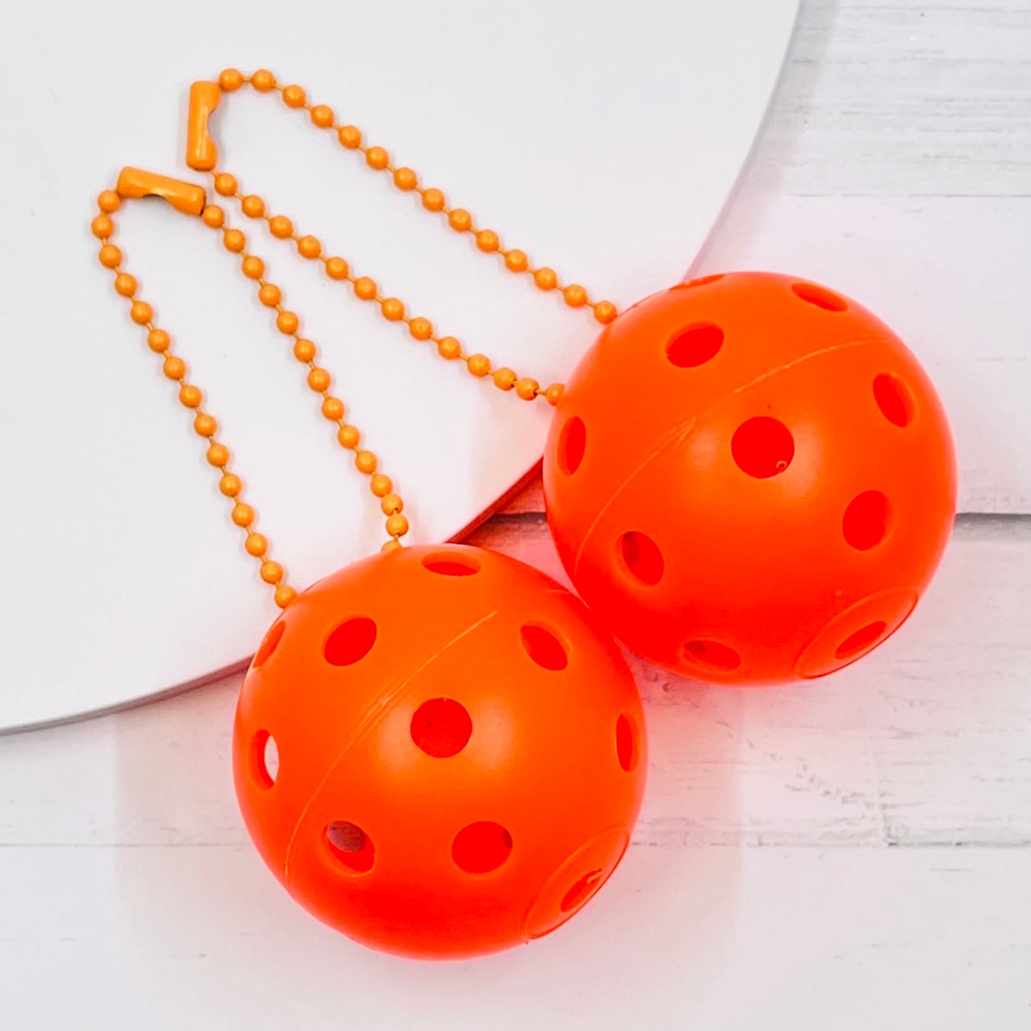 Mini Pickleball Bag Tags/Pulls (Set of 2)  Each order gets you 2 of the little mini pickleballs and chain! They measure about 1 1/2 inches and are used as bag tag markers. Fun for any bag, especially your pickleball bag!! The balls come in 7 colors: Red, Green, Blue, Orange, White, Pink, and Yellow. Choose 2 of the 7 fun colors.