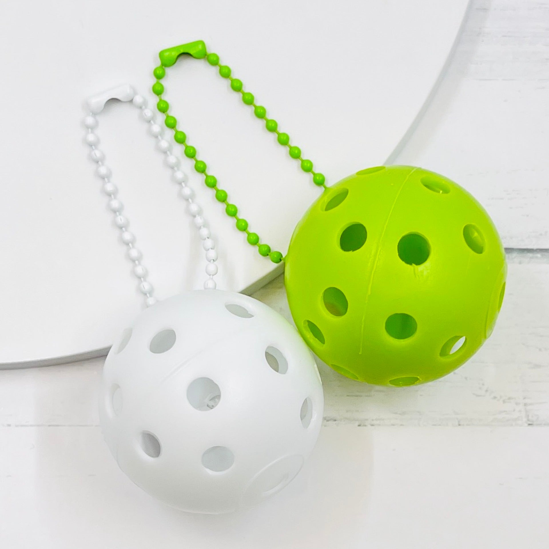 Mini Pickleball Bag Tags/Pulls (Set of 2)  Each order gets you 2 of the little mini pickleballs and chain! They measure about 1 1/2 inches and are used as bag tag markers. Fun for any bag, especially your pickleball bag!! The balls come in 7 colors: Red, Green, Blue, Orange, White, Pink, and Yellow. Choose 2 of the 7 fun colors.