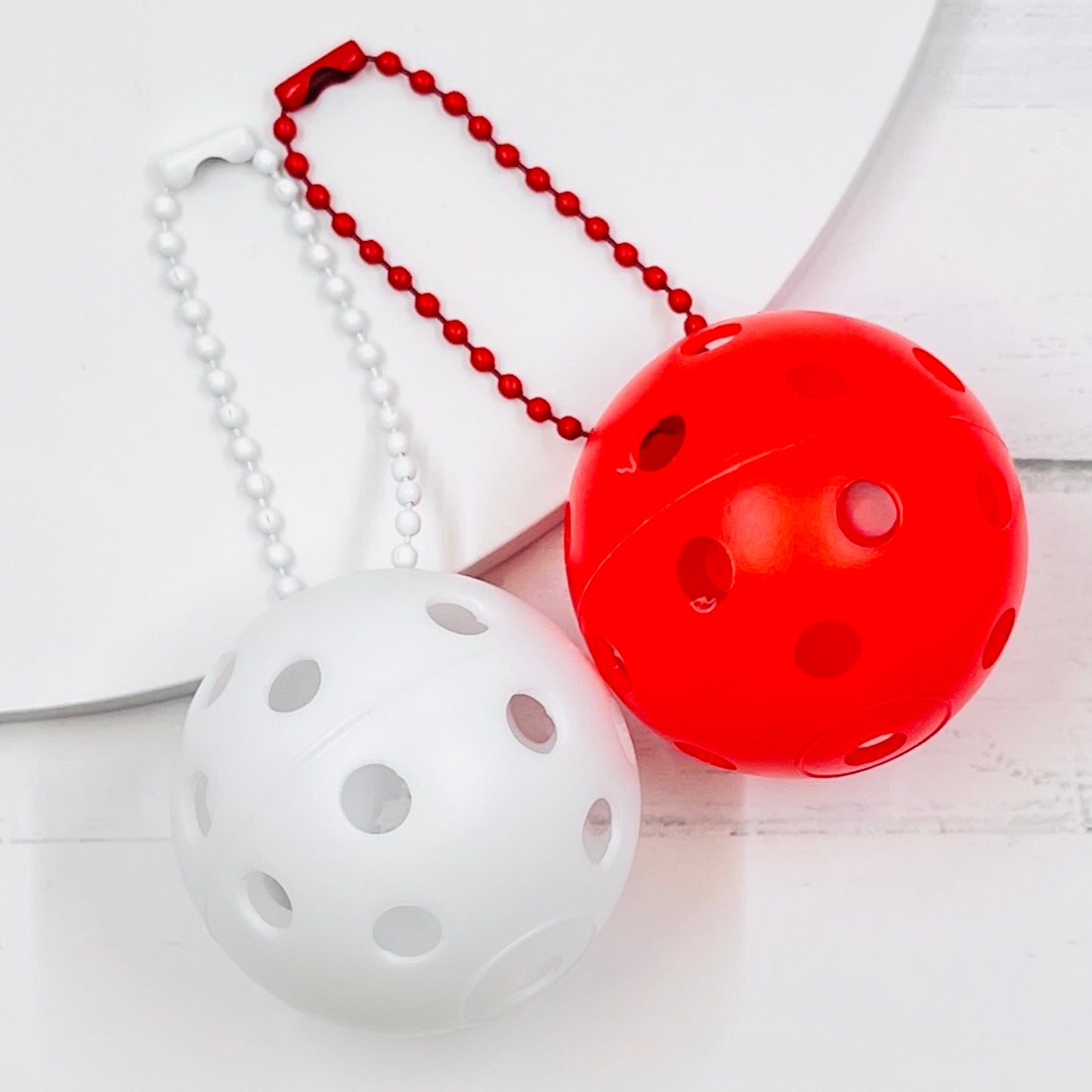 Mini Pickleball Bag Tags/Pulls (Set of 2)  Each order gets you 2 of the little mini pickleballs and chain! They measure about 1 1/2 inches and are used as bag tag markers. Fun for any bag, especially your pickleball bag!! The balls come in 7 colors: Red, Green, Blue, Orange, White, Pink, and Yellow. Choose 2 of the 7 fun colors.