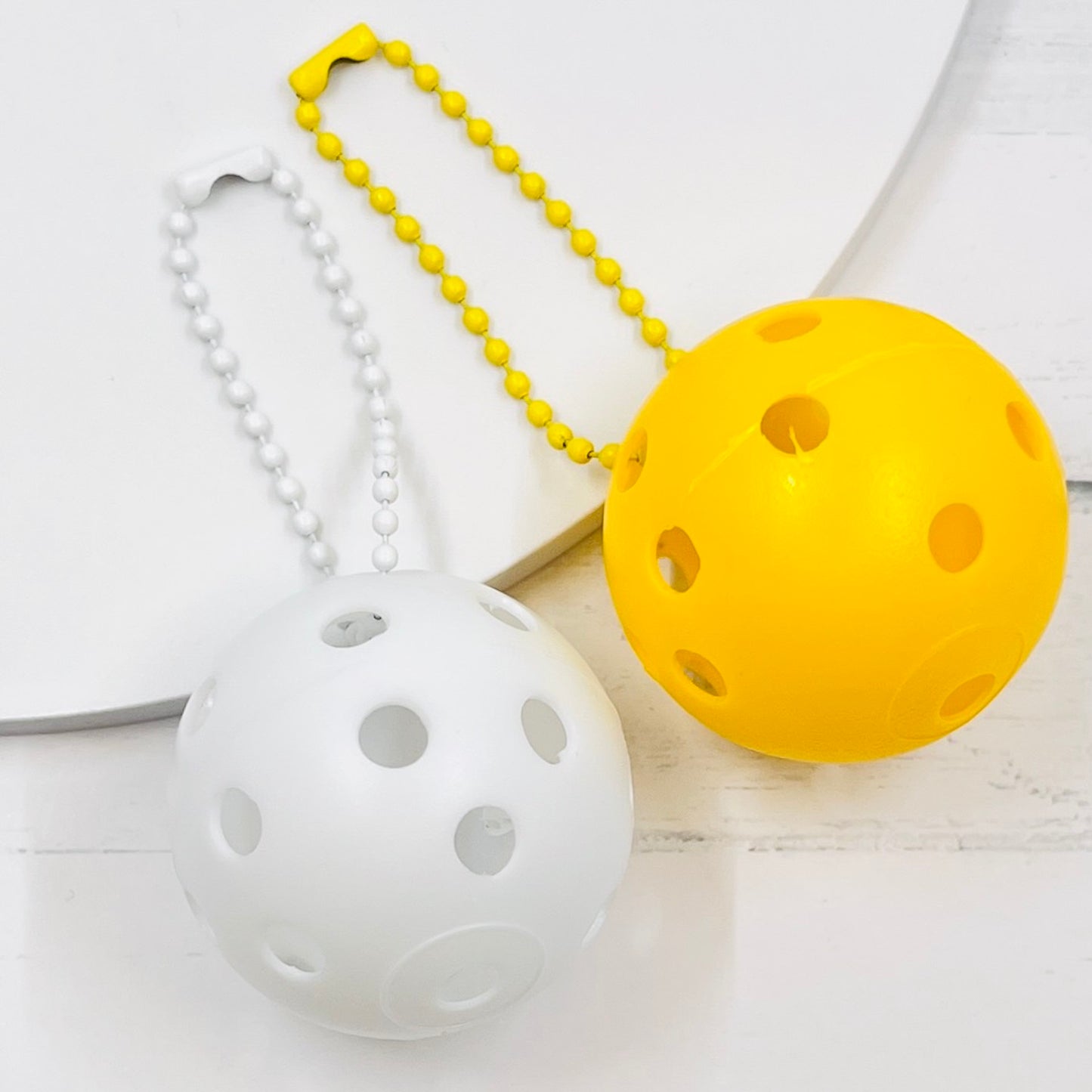 Mini Pickleball Bag Tags/Pulls (Set of 2)  Each order gets you 2 of the little mini pickleballs and chain! They measure about 1 1/2 inches and are used as bag tag markers. Fun for any bag, especially your pickleball bag!! The balls come in 7 colors: Red, Green, Blue, Orange, White, Pink, and Yellow. Choose 2 of the 7 fun colors.