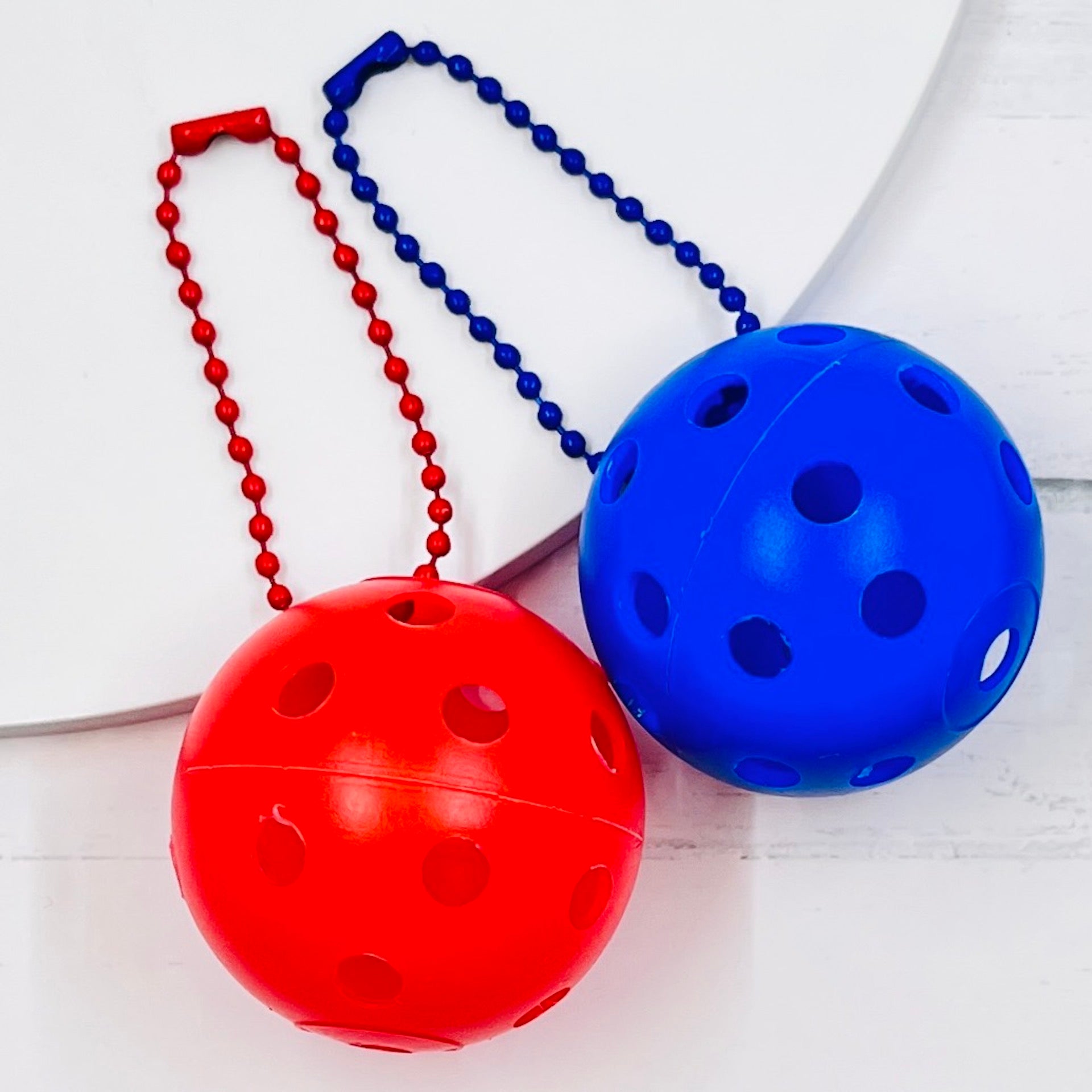 Mini Pickleball Bag Tags/Pulls (Set of 2)  Each order gets you 2 of the little mini pickleballs and chain! They measure about 1 1/2 inches and are used as bag tag markers. Fun for any bag, especially your pickleball bag!! The balls come in 7 colors: Red, Green, Blue, Orange, White, Pink, and Yellow. Choose 2 of the 7 fun colors.