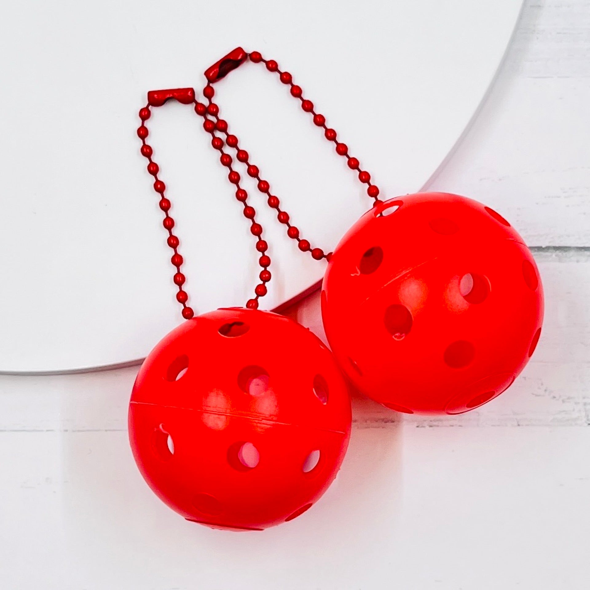 Mini Pickleball Bag Tags/Pulls (Set of 2)  Each order gets you 2 of the little mini pickleballs and chain! They measure about 1 1/2 inches and are used as bag tag markers. Fun for any bag, especially your pickleball bag!! The balls come in 7 colors: Red, Green, Blue, Orange, White, Pink, and Yellow. Choose 2 of the 7 fun colors.