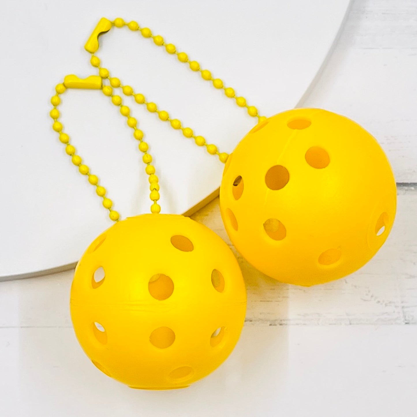 Mini Pickleball Bag Tags/Pulls (Set of 2)  Each order gets you 2 of the little mini pickleballs and chain! They measure about 1 1/2 inches and are used as bag tag markers. Fun for any bag, especially your pickleball bag!! The balls come in 7 colors: Red, Green, Blue, Orange, White, Pink, and Yellow. Choose 2 of the 7 fun colors.