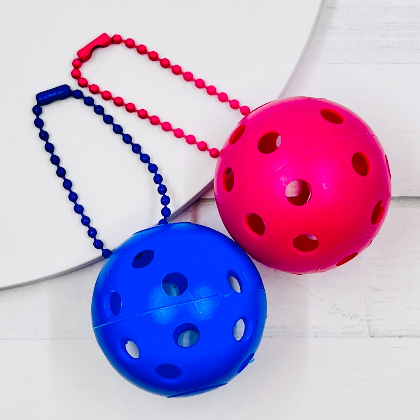 Mini Pickleball Bag Tags/Pulls (Set of 2)  Each order gets you 2 of the little mini pickleballs and chain! They measure about 1 1/2 inches and are used as bag tag markers. Fun for any bag, especially your pickleball bag!! The balls come in 7 colors: Red, Green, Blue, Orange, White, Pink, and Yellow. Choose 2 of the 7 fun colors.