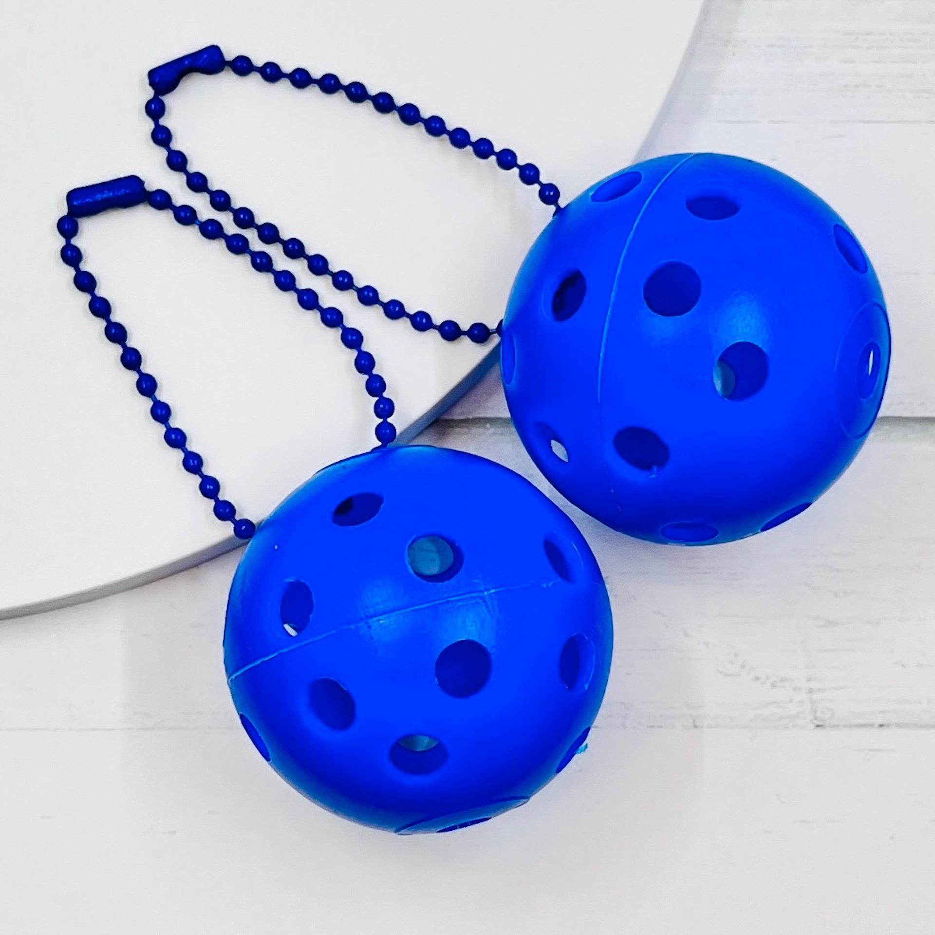 Mini Pickleball Bag Tags/Pulls (Set of 2)  Each order gets you 2 of the little mini pickleballs and chain! They measure about 1 1/2 inches and are used as bag tag markers. Fun for any bag, especially your pickleball bag!! The balls come in 7 colors: Red, Green, Blue, Orange, White, Pink, and Yellow. Choose 2 of the 7 fun colors.