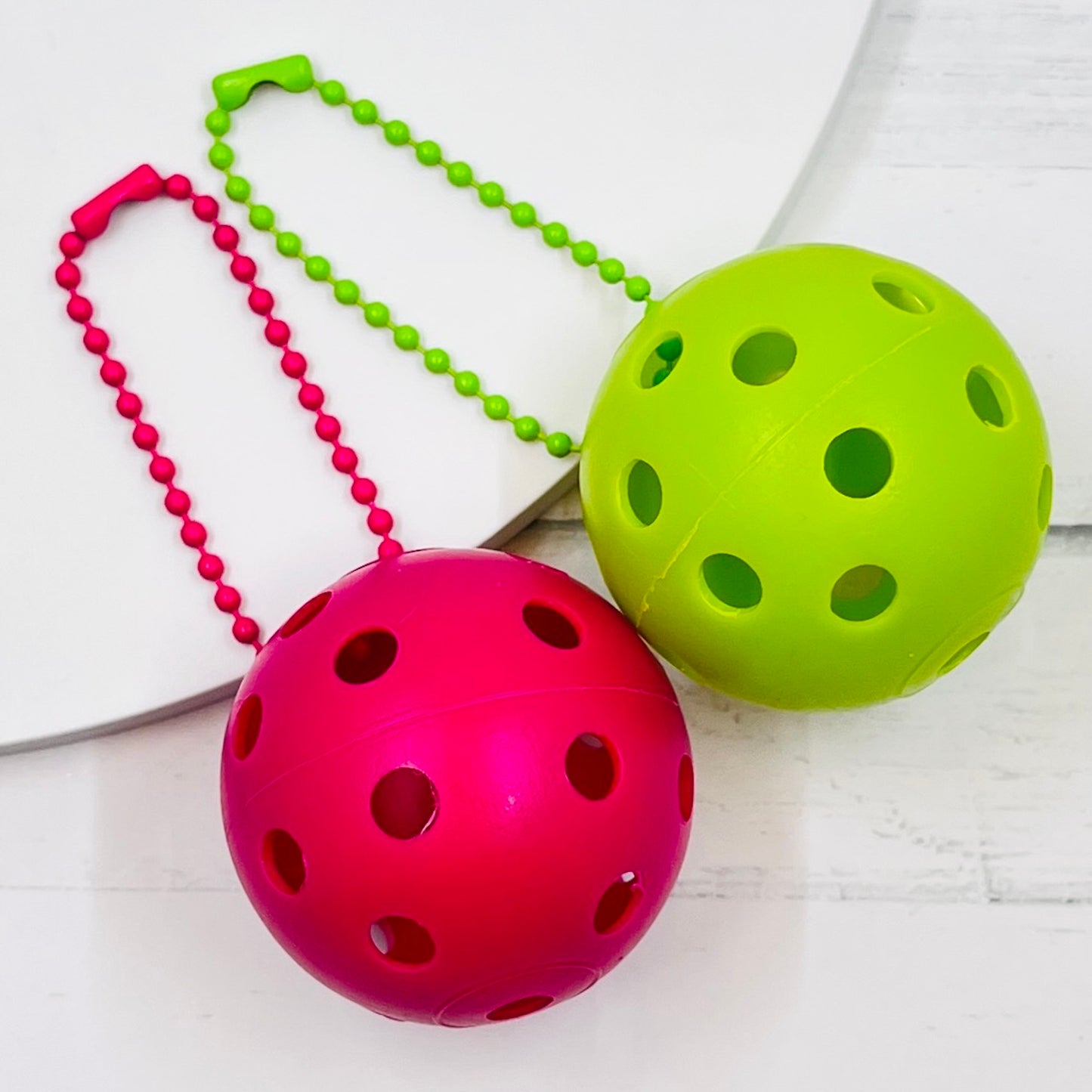 Mini Pickleball Bag Tags/Pulls (Set of 2)  Each order gets you 2 of the little mini pickleballs and chain! They measure about 1 1/2 inches and are used as bag tag markers. Fun for any bag, especially your pickleball bag!! The balls come in 7 colors: Red, Green, Blue, Orange, White, Pink, and Yellow. Choose 2 of the 7 fun colors.